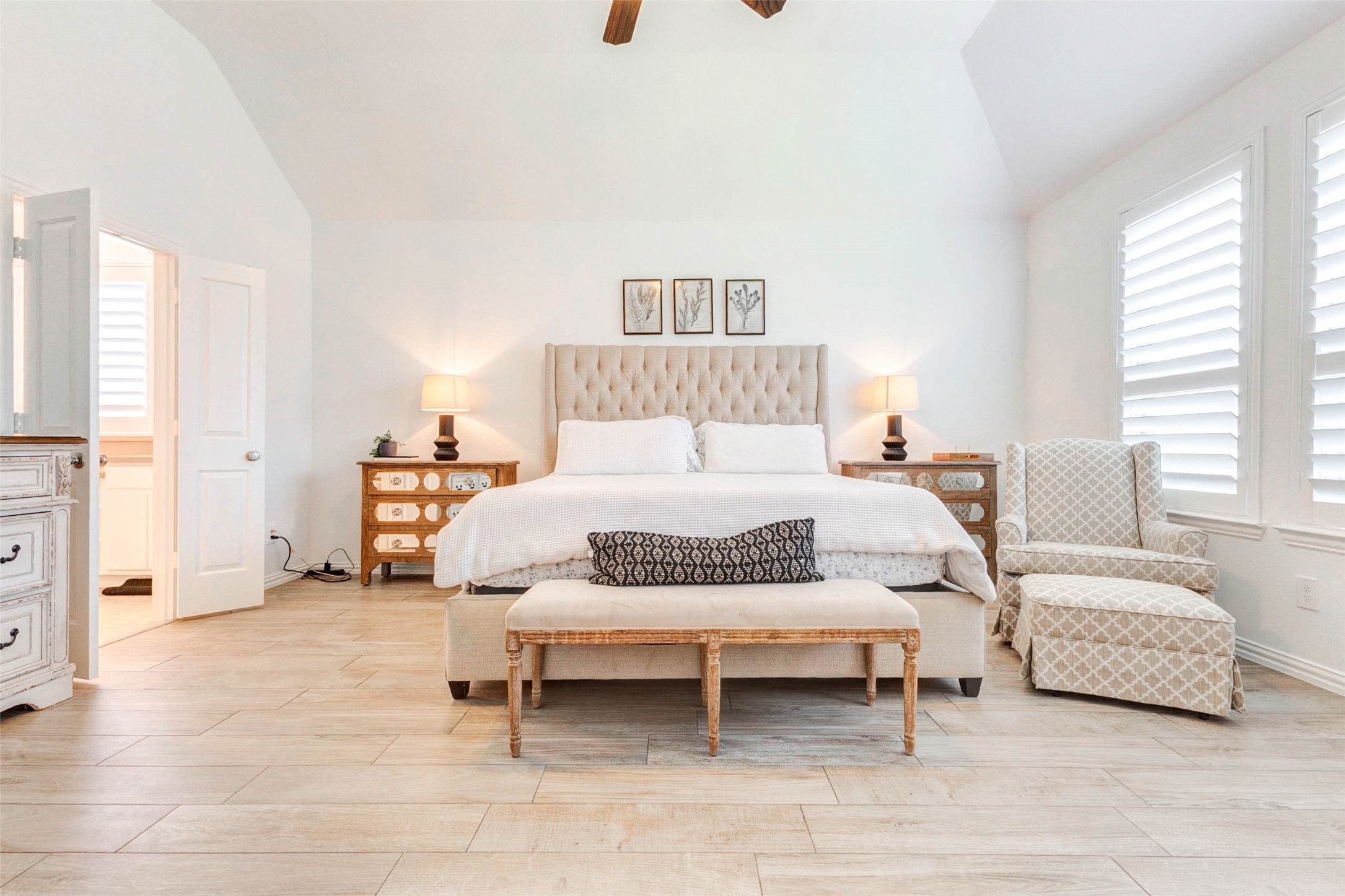 This beautifully designed primary suite offers a tranquil escape with a spacious layout and elegant finishes. The tray ceiling enhances the sense of openness, while soft natural light filters through plantation shutters. A stylish seating area adds comfort and charm, and the neutral palette creates a calming atmosphere. This private retreat provides the perfect balance of luxury and everyday comfort.