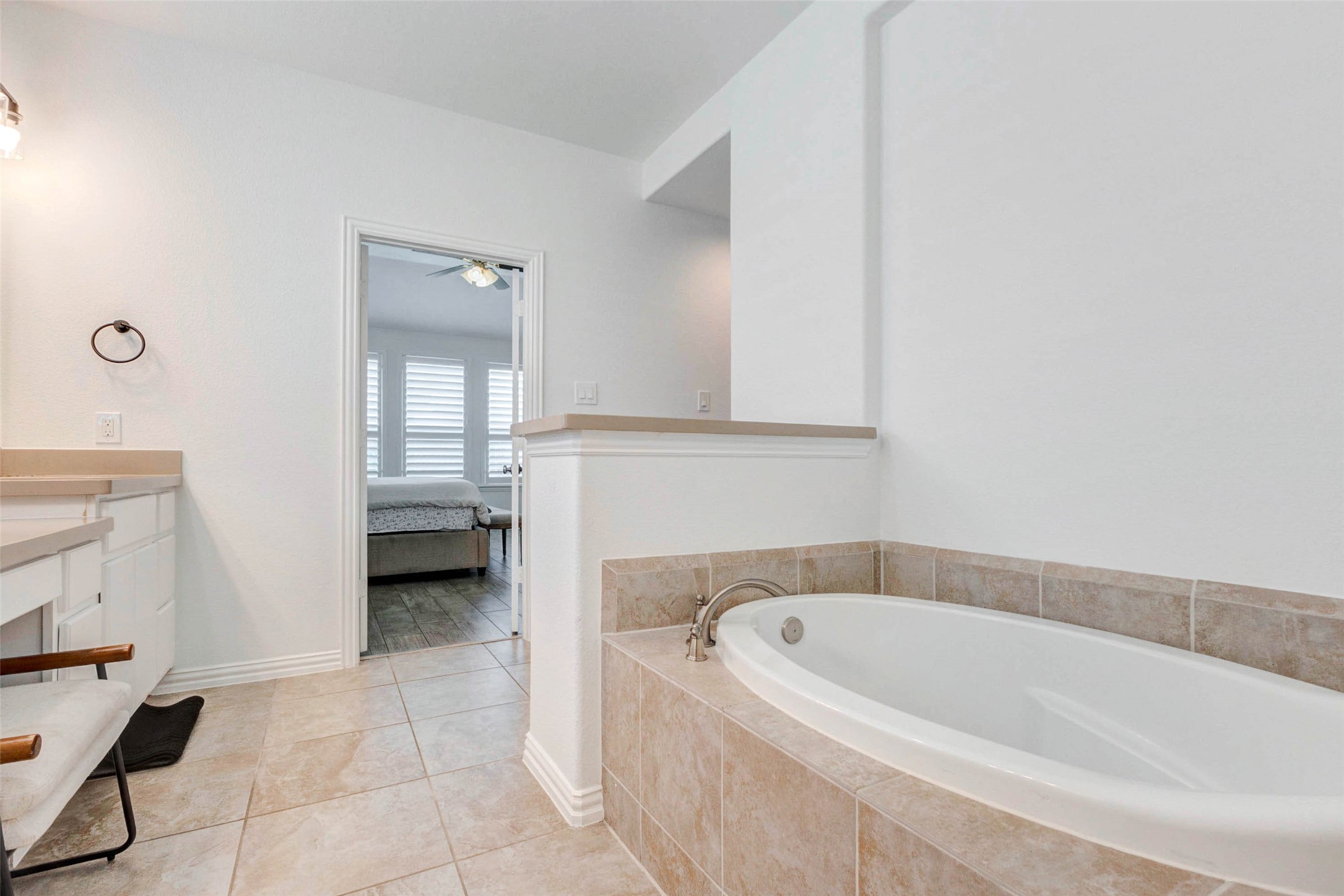 Relax and unwind in this spa-like soaking tub, perfectly positioned within a serene and private bathroom setting. Surrounded by neutral tile and clean finishes, the space offers a calming retreat at the end of the day. The open layout flows seamlessly into the vanity area and connects directly to the primary bedroom, creating a functional and peaceful environment designed for both comfort and relaxation.