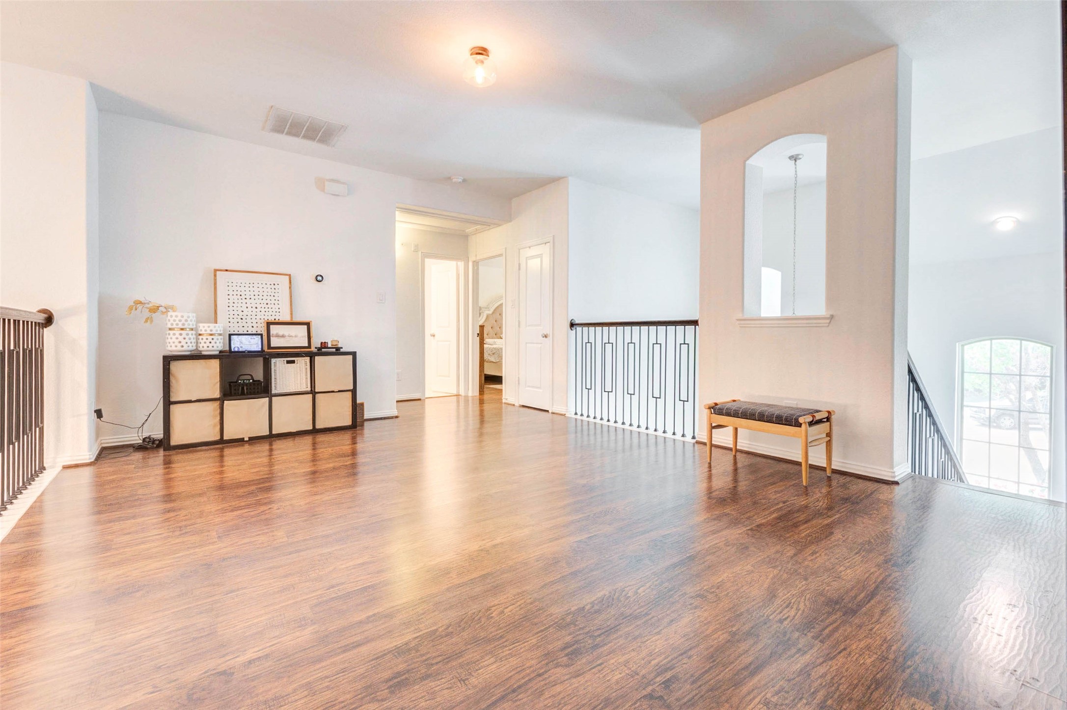 This spacious upstairs landing offers incredible flexibility, perfect for a game room, media area, or secondary living space. Rich wood flooring adds warmth, while the open railing overlooks the lower level, creating a bright and connected feel. Natural light flows in from nearby windows, enhancing the airy atmosphere. With ample wall space and an open layout, this versatile area can easily adapt to your lifestyle needs.