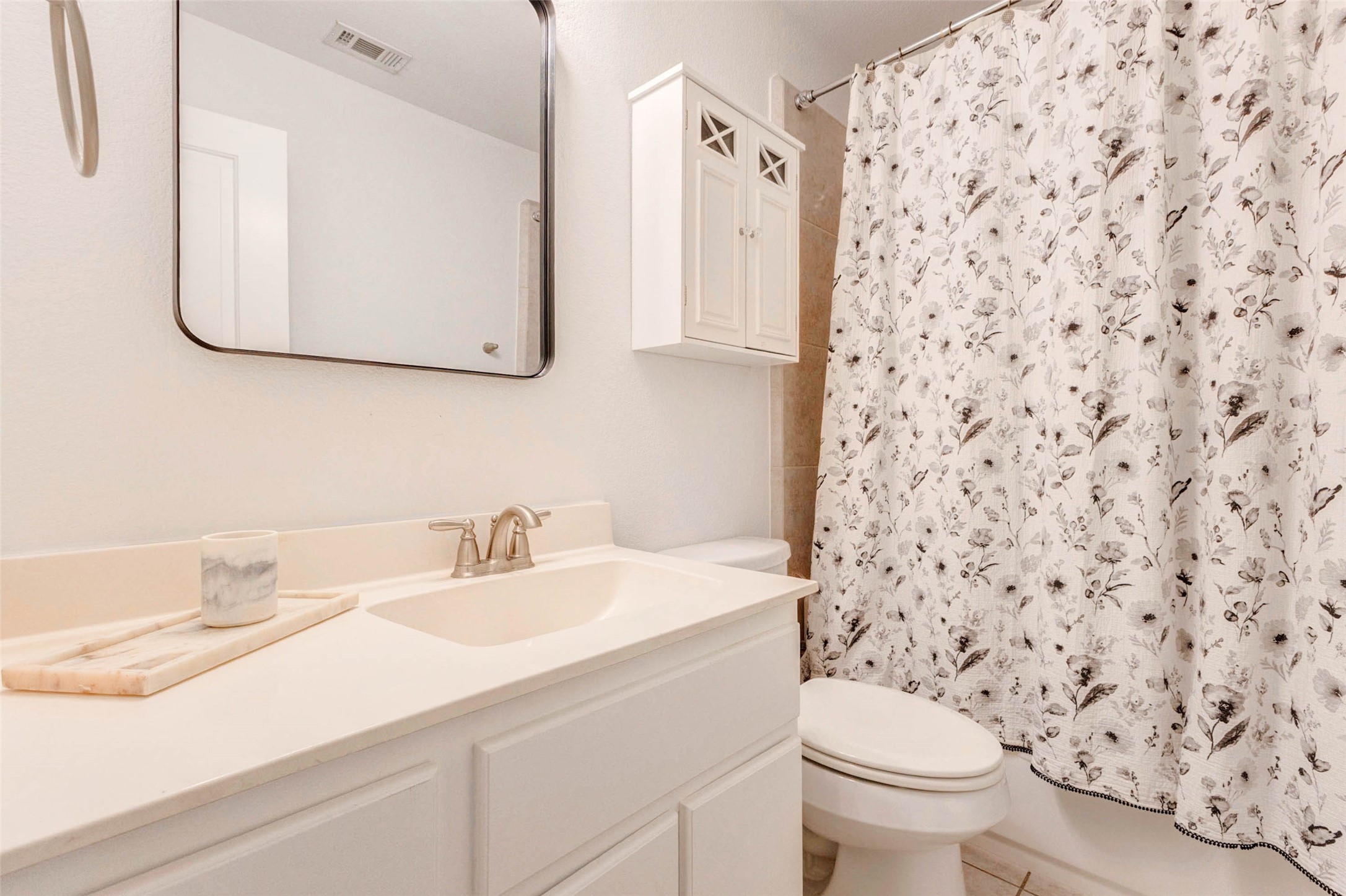 This well-appointed bathroom features a clean and functional layout with a spacious vanity and ample counter space. The large mirror enhances the sense of openness, while the neutral tones create a calming environment. A shower and tub combination with updated fixtures offers convenience for daily routines. Built-in storage and bright lighting make this bathroom practical and comfortable.