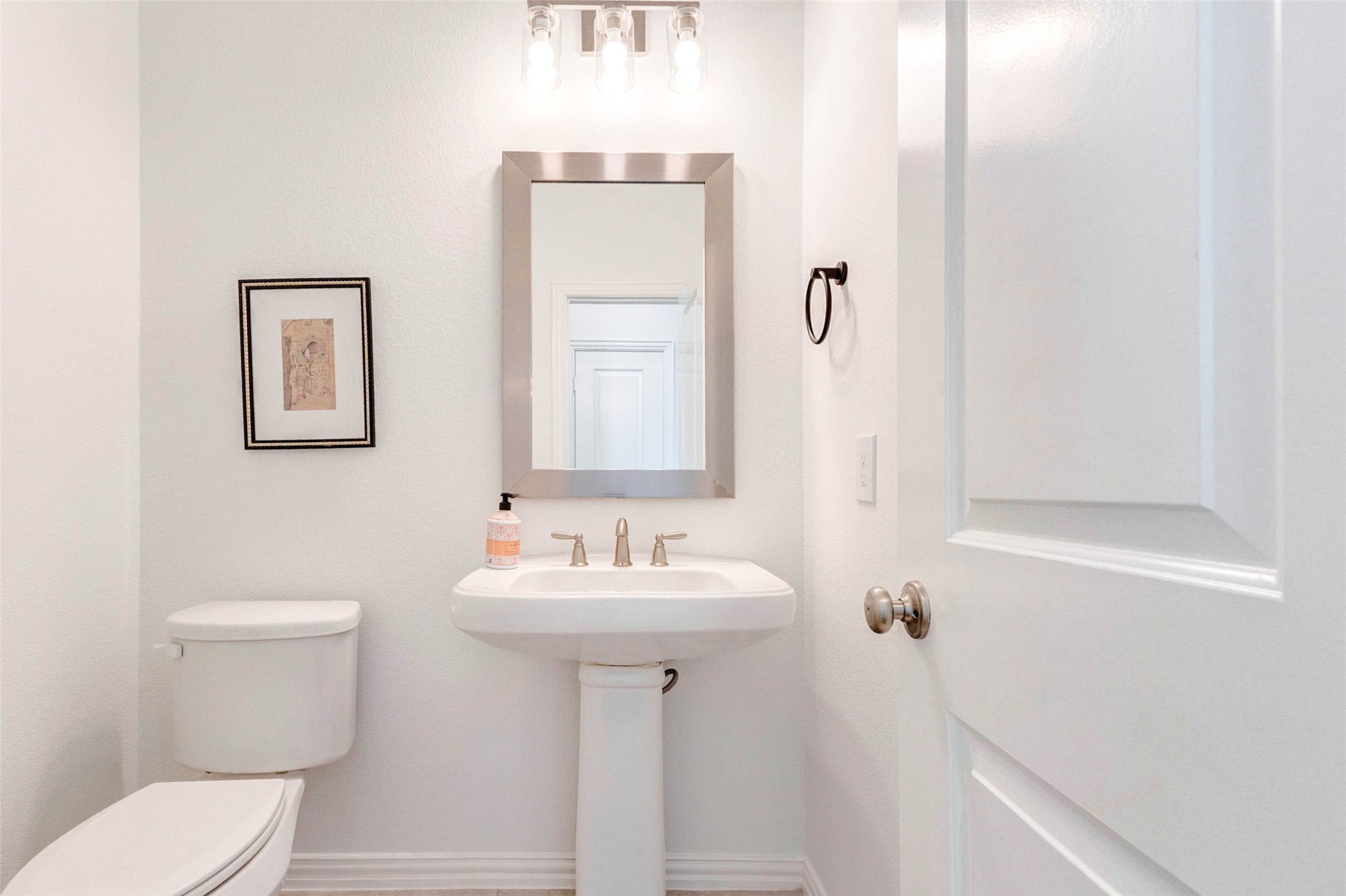 This conveniently located powder bath offers a clean and polished design with a pedestal sink and classic finishes. Bright lighting and a neutral color scheme create a fresh, welcoming feel for guests. The compact layout maximizes functionality without sacrificing style, making it a perfect addition for entertaining and everyday convenience.