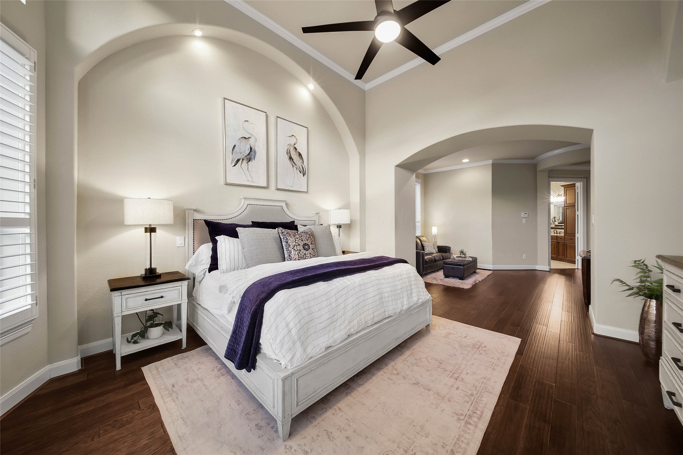 Architectural arches, rich wood floors, built-in shelving, and classic shutters create a beautifully refined look in the primary bedroom, blending timeless elegance with thoughtful design.