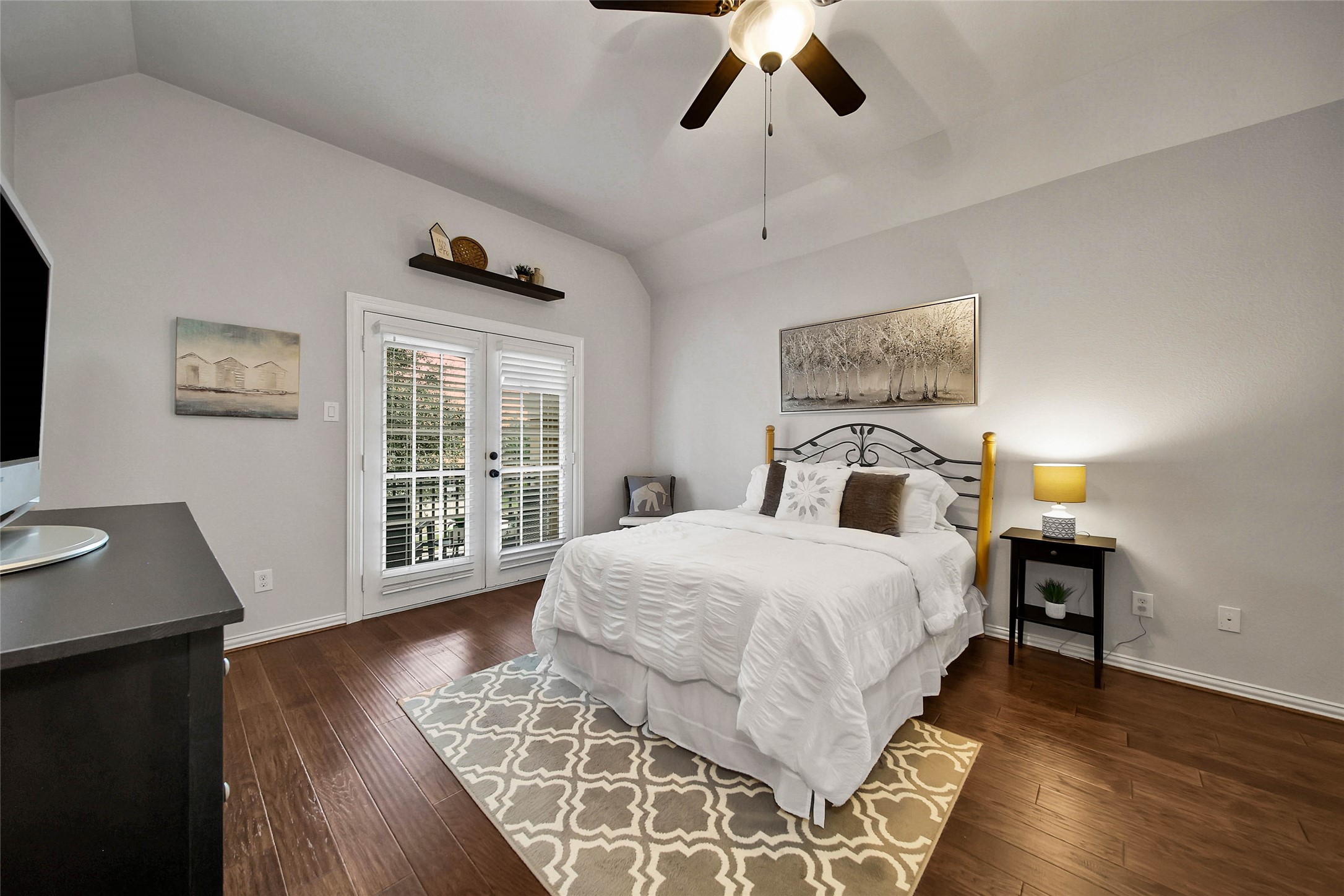 The guest bedroom features a ceiling fan, walk-in closet, and private balcony, creating a comfortable retreat with its own outdoor escape.