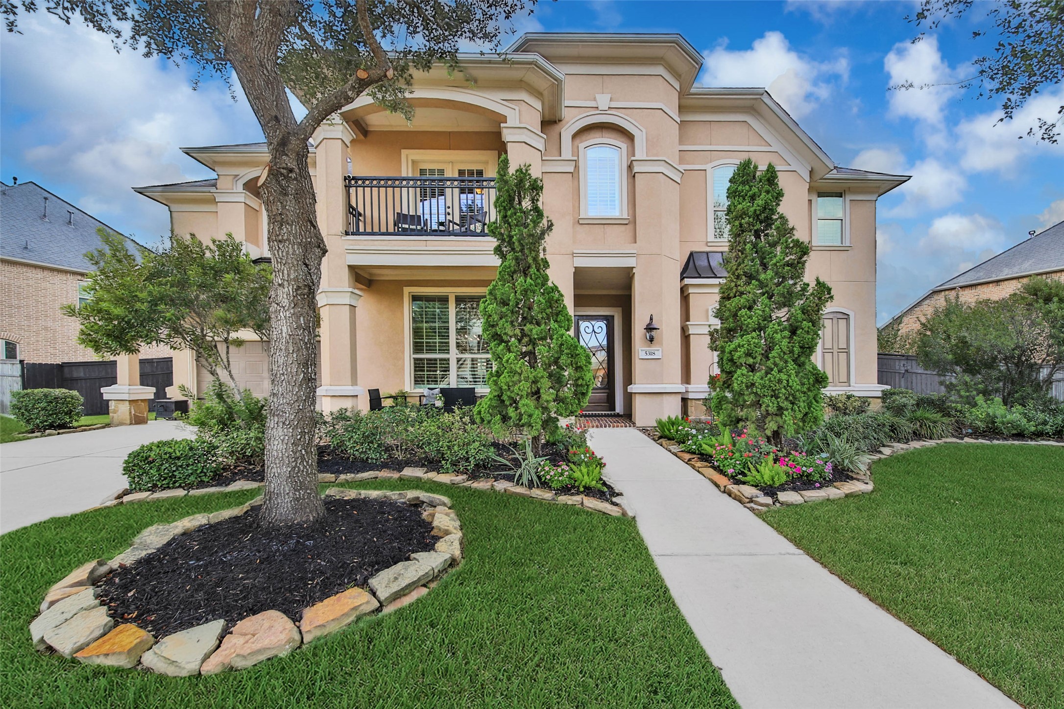 The professionally landscaped yard, featuring mature shrubs, vibrant color, and fresh sod, creates striking curb appeal and a warm welcome for guests.