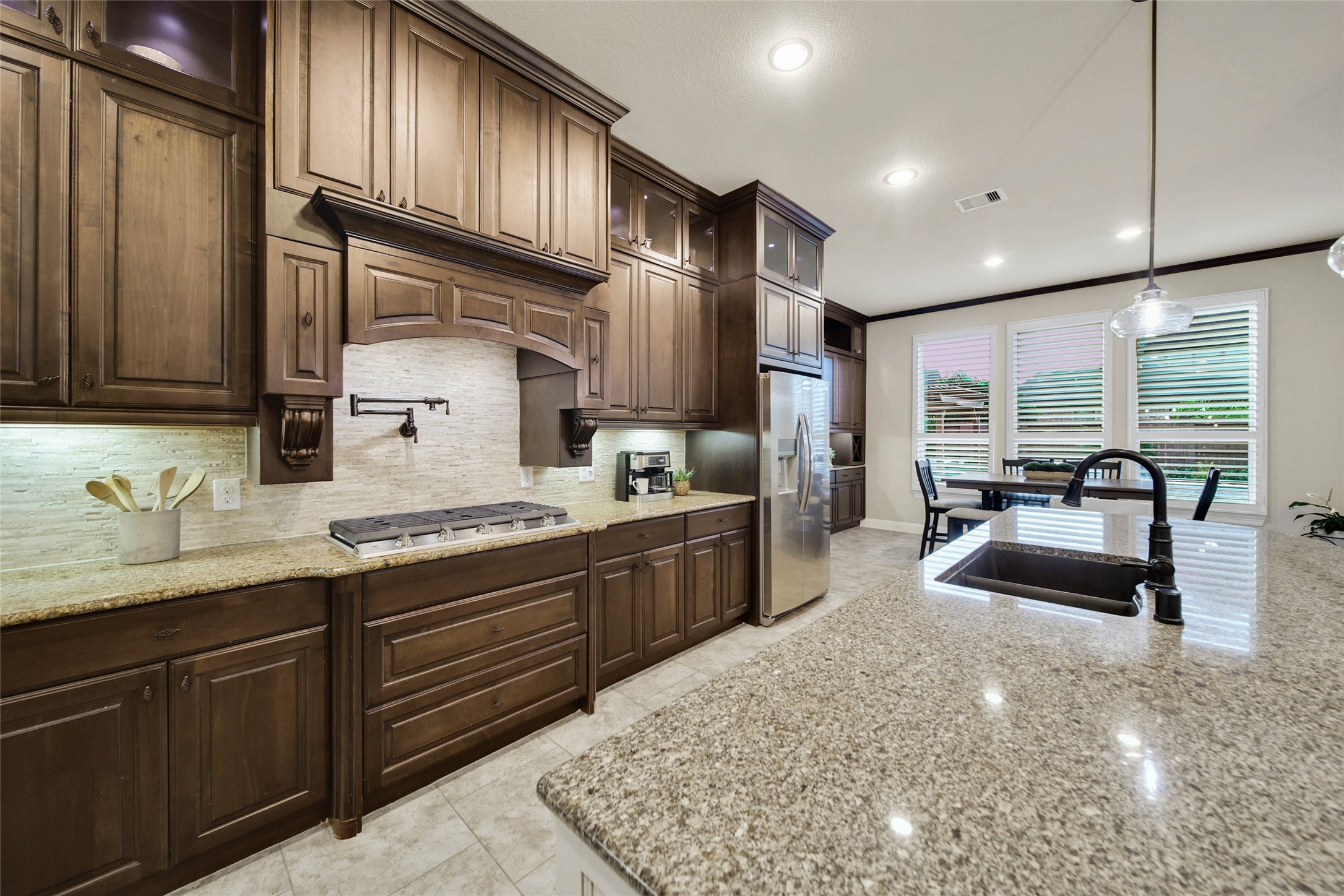 The beautiful stacked travertine backsplash adds timeless elegance, perfectly complementing the cabinetry and countertops while elevating the kitchens overall design.