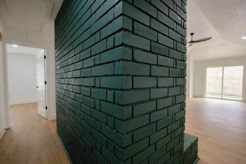 Chic and modern interior featuring a striking dark green brick accent wall, light wood style flooring, and ample natural light pouring through large sliding glass doors.