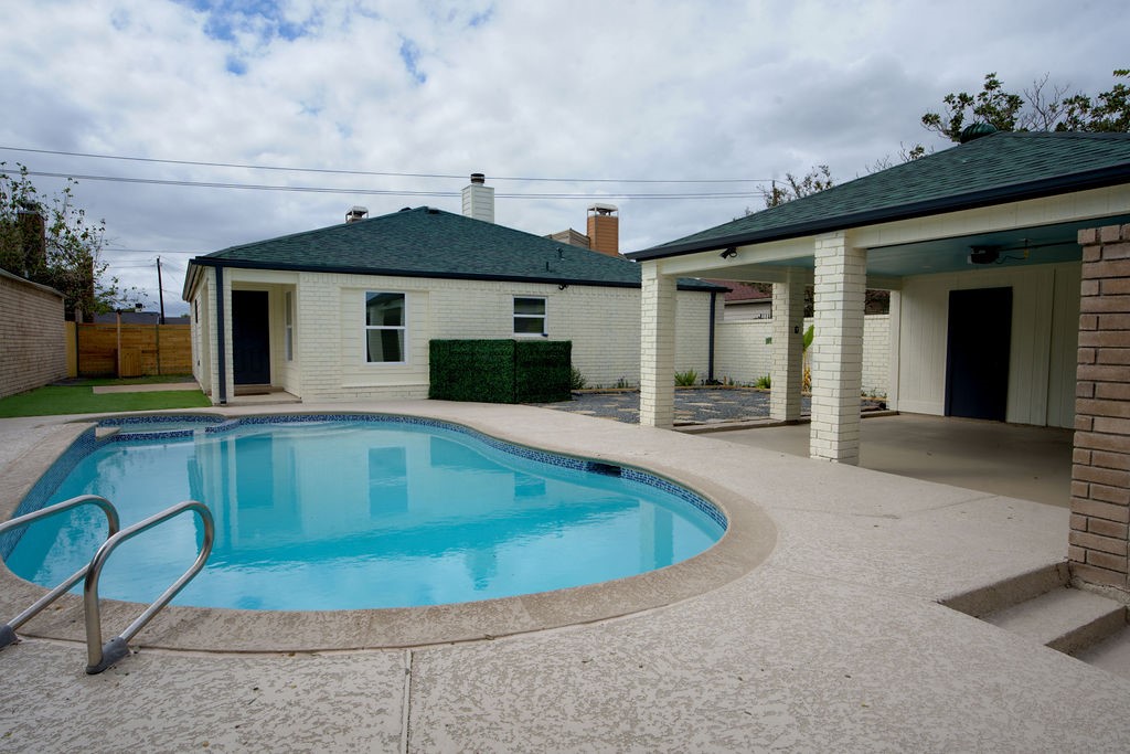 Charming backyard oasis featuring a refreshing pool, spacious patio area, and covered outdoor space perfect for entertaining.