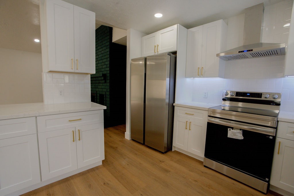 Modern kitchen with sleek stainless steel appliances, elegant white cabinetry, and warm hardwood style flooring.