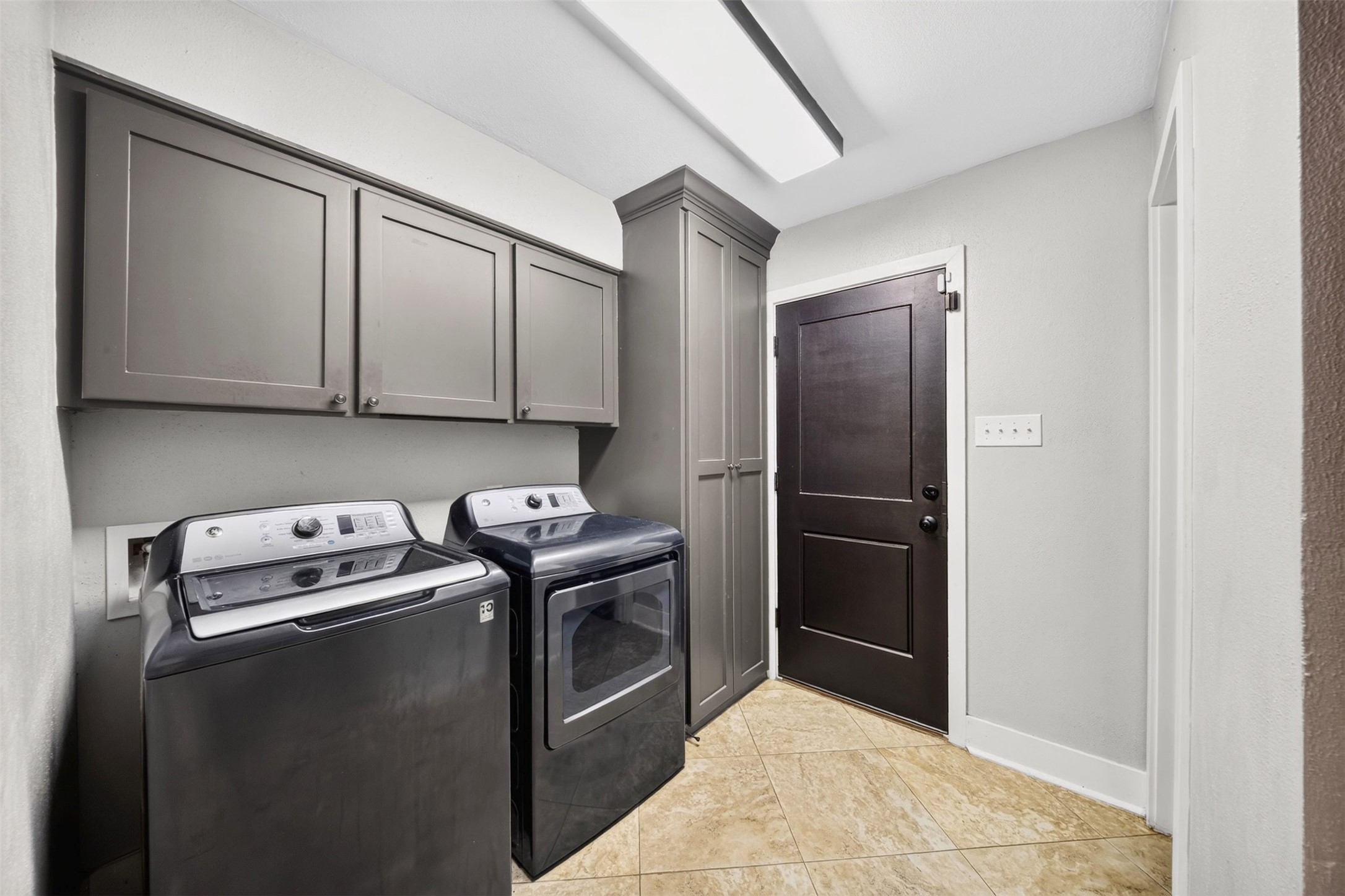 Utility Room / Laundry
Conveniently designed laundry room featuring upper and full-height cabinetry, tile flooring, and space for a full-size washer and dryer. Practical storage and functionality complement the home's thoughtful layout.