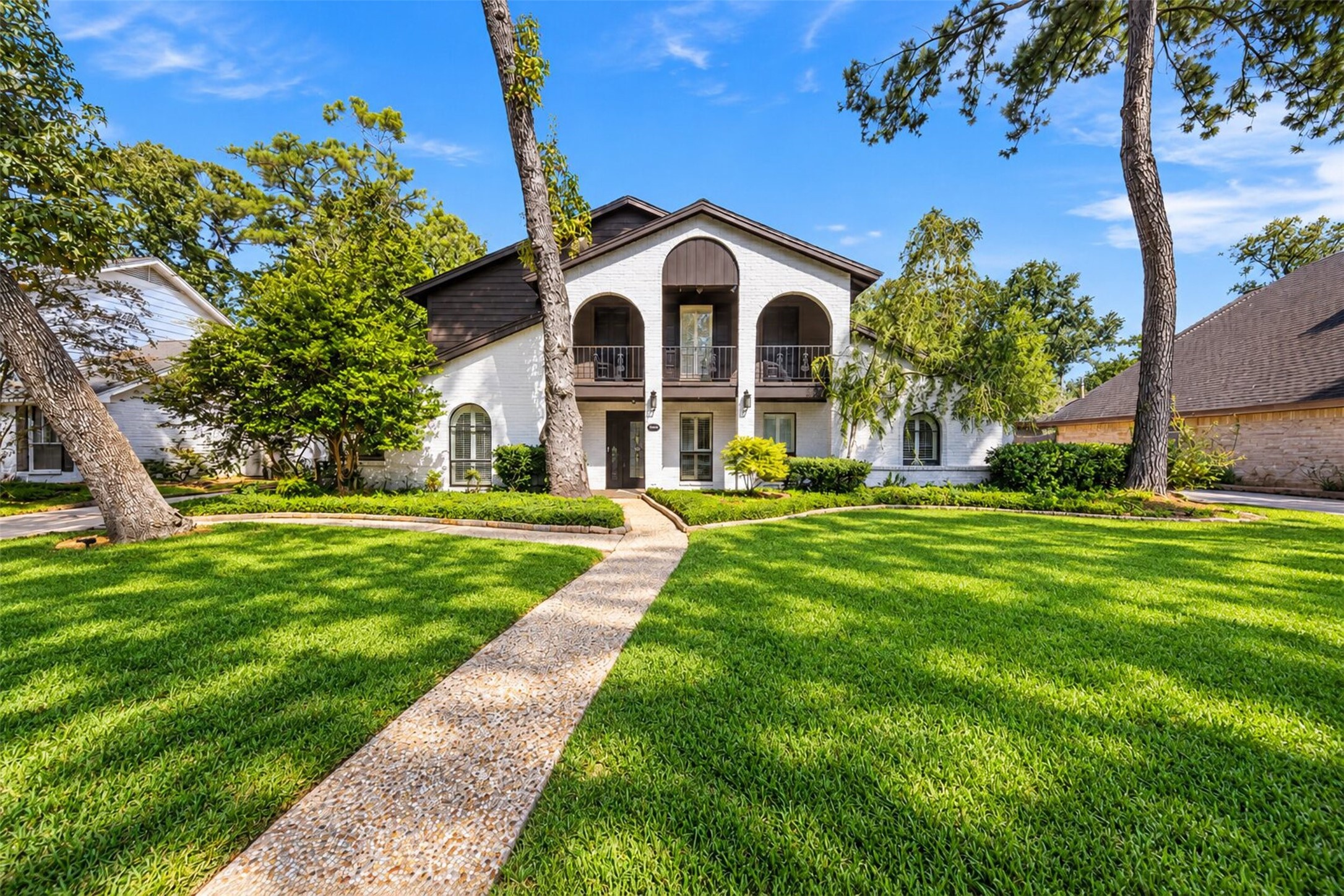 Front Exterior
Beautiful two-story home showcasing timeless painted brick, distinctive arched architecture, an upper-level balcony, mature trees, and beautifully maintained landscaping that creates impressive curb appeal.