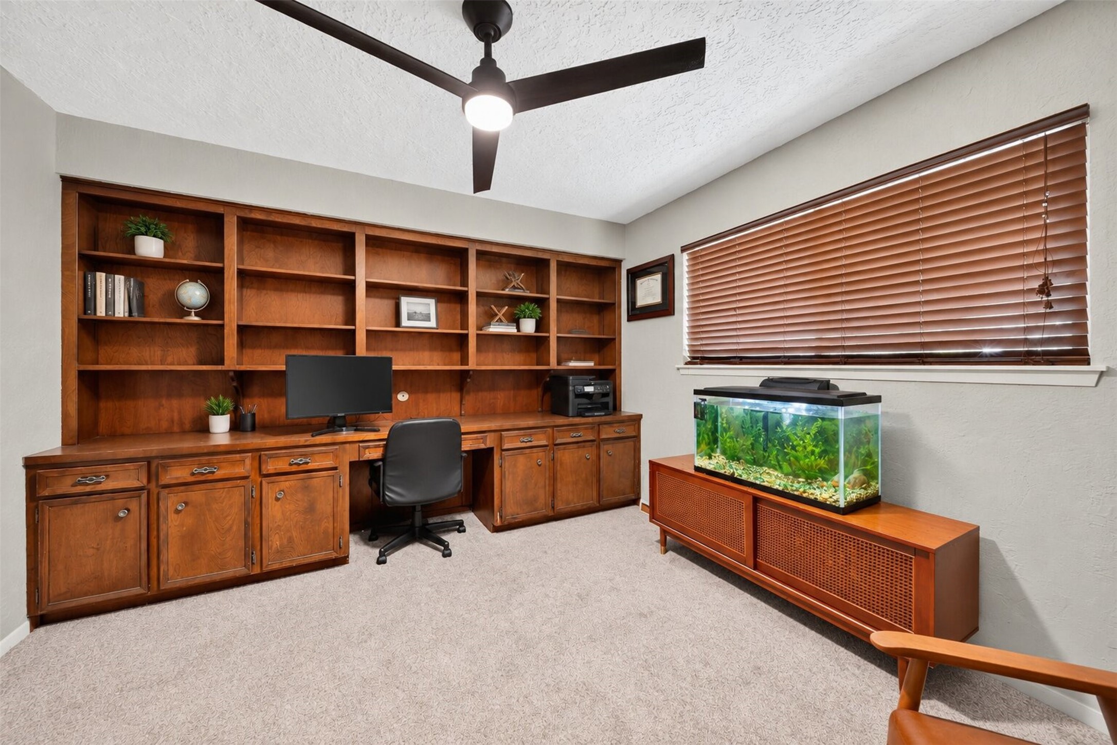 Private Home Office / Study
Dedicated home office featuring expansive built-in wood cabinetry, generous shelving, a spacious workstation, and a ceiling fan. An ideal setting for productivity and organization.