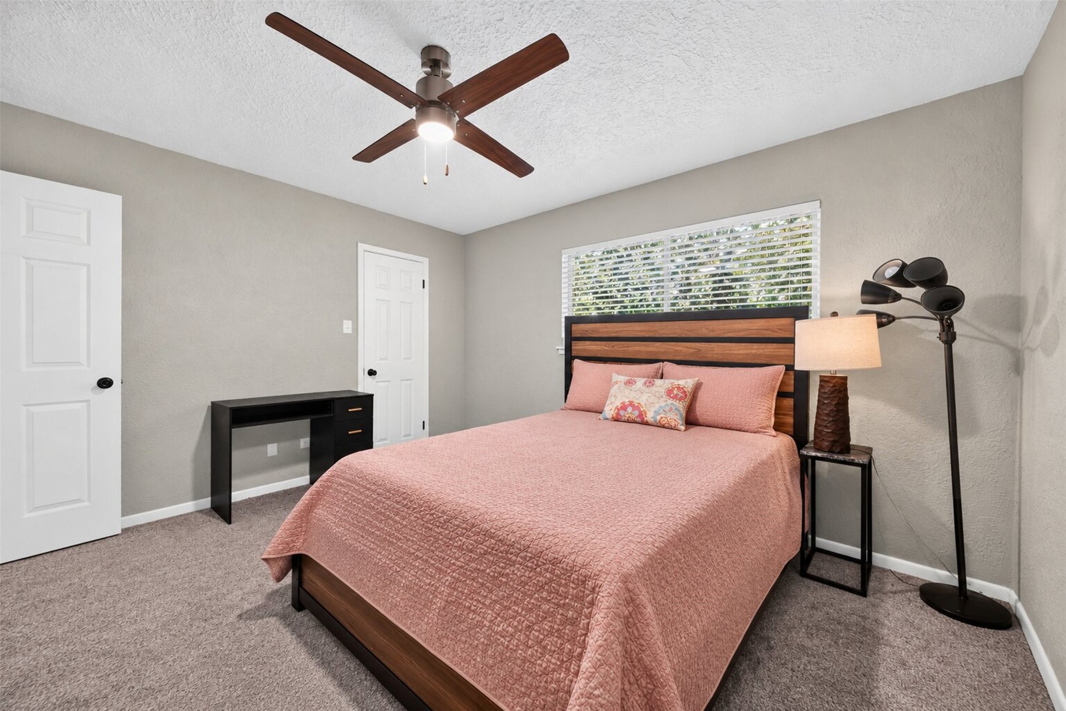 Secondary Bedroom: Spacious secondary bedroom offering neutral finishes, plush carpeting, a ceiling fan, and a large window providing natural light.