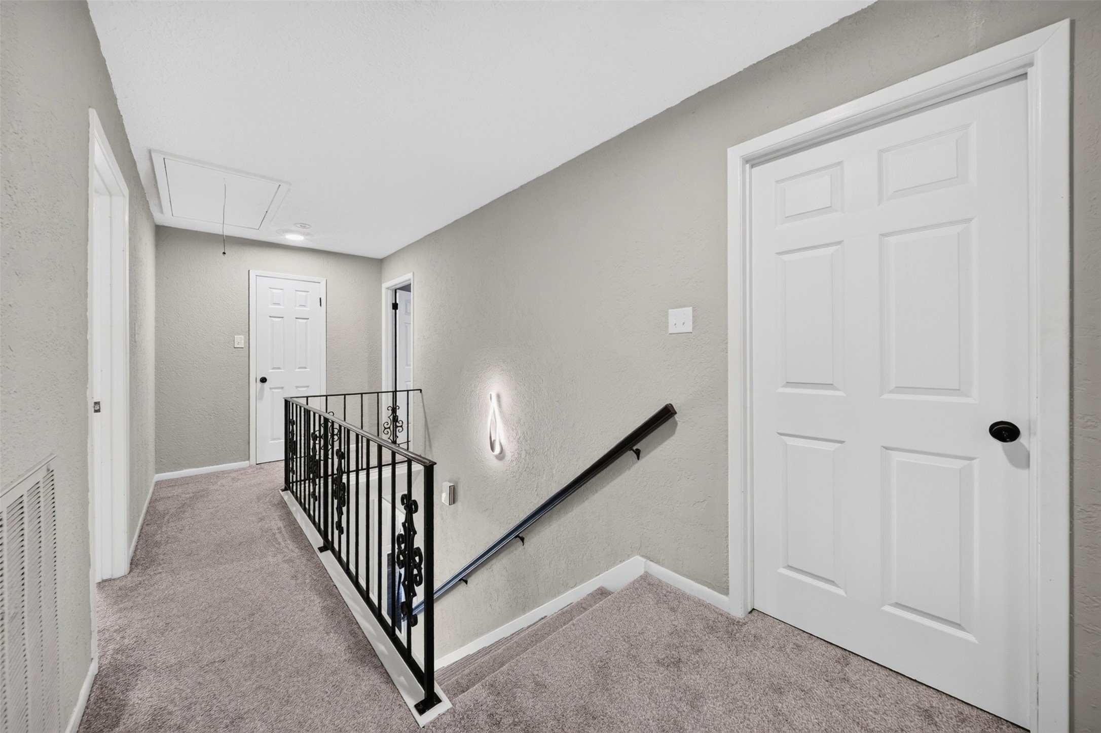 Upstairs Landing / Hallway
Upstairs landing featuring neutral finishes, carpeting, decorative wrought-iron railing, and convenient access to the second-floor rooms.
