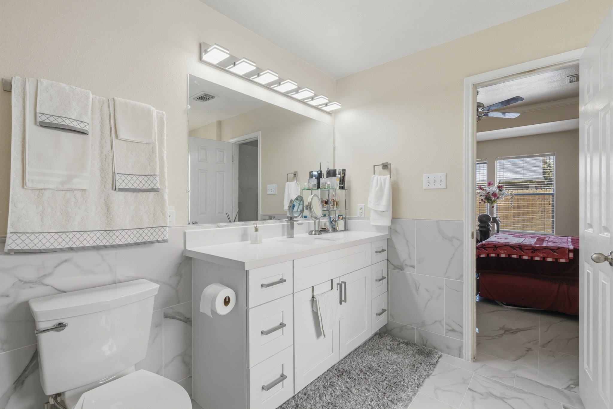 The remodeled primary bath includes a long vanity with generous storage, bright lighting and an open connection to the bedroom.
