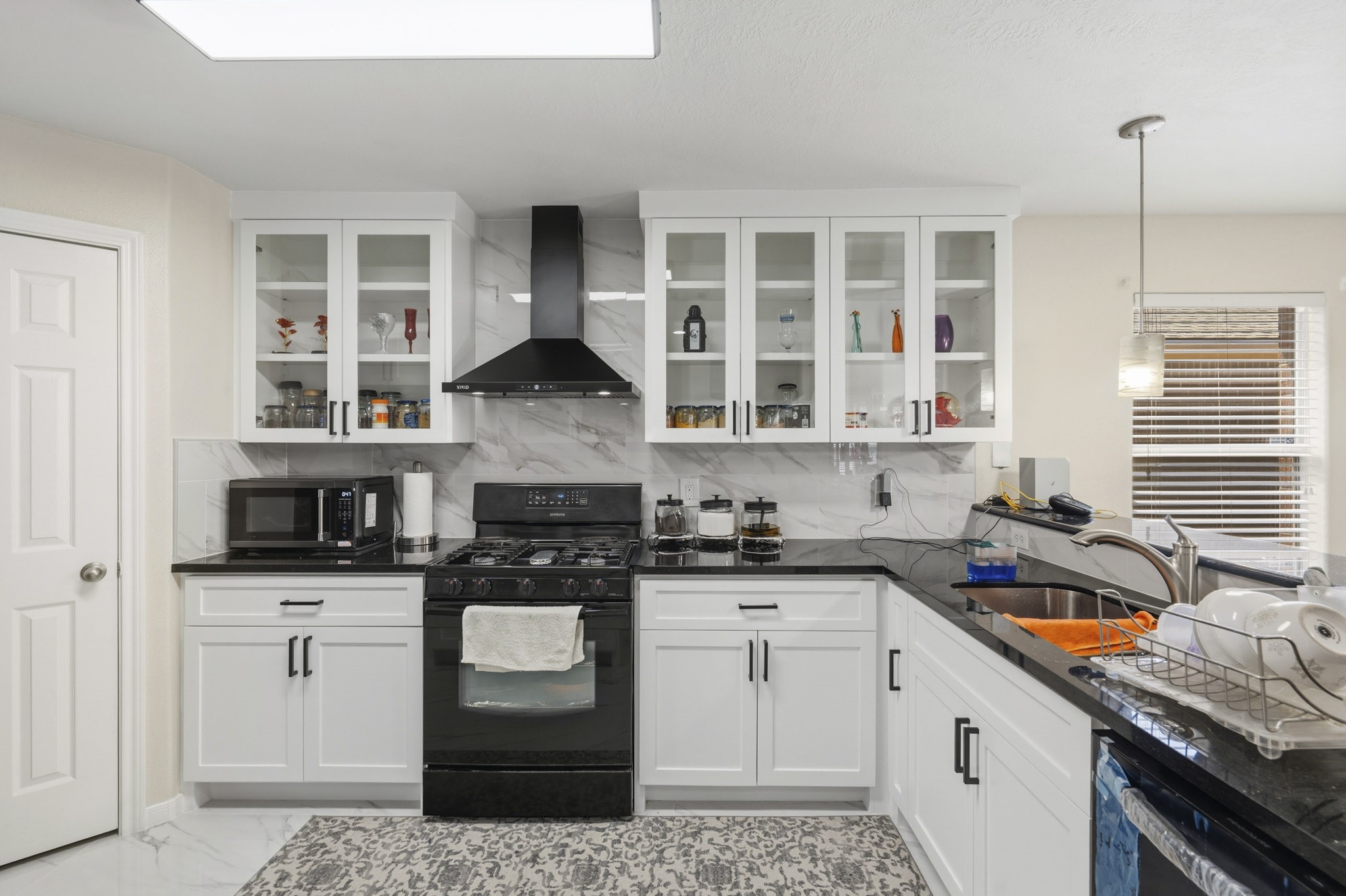 Sleek finishes, glass-front cabinetry and a striking vent hood give the remodeled kitchen a fresh, polished look. Sleek finishes, glass-front cabinetry and a striking vent hood give the remodeled kitchen a fresh, polished look.