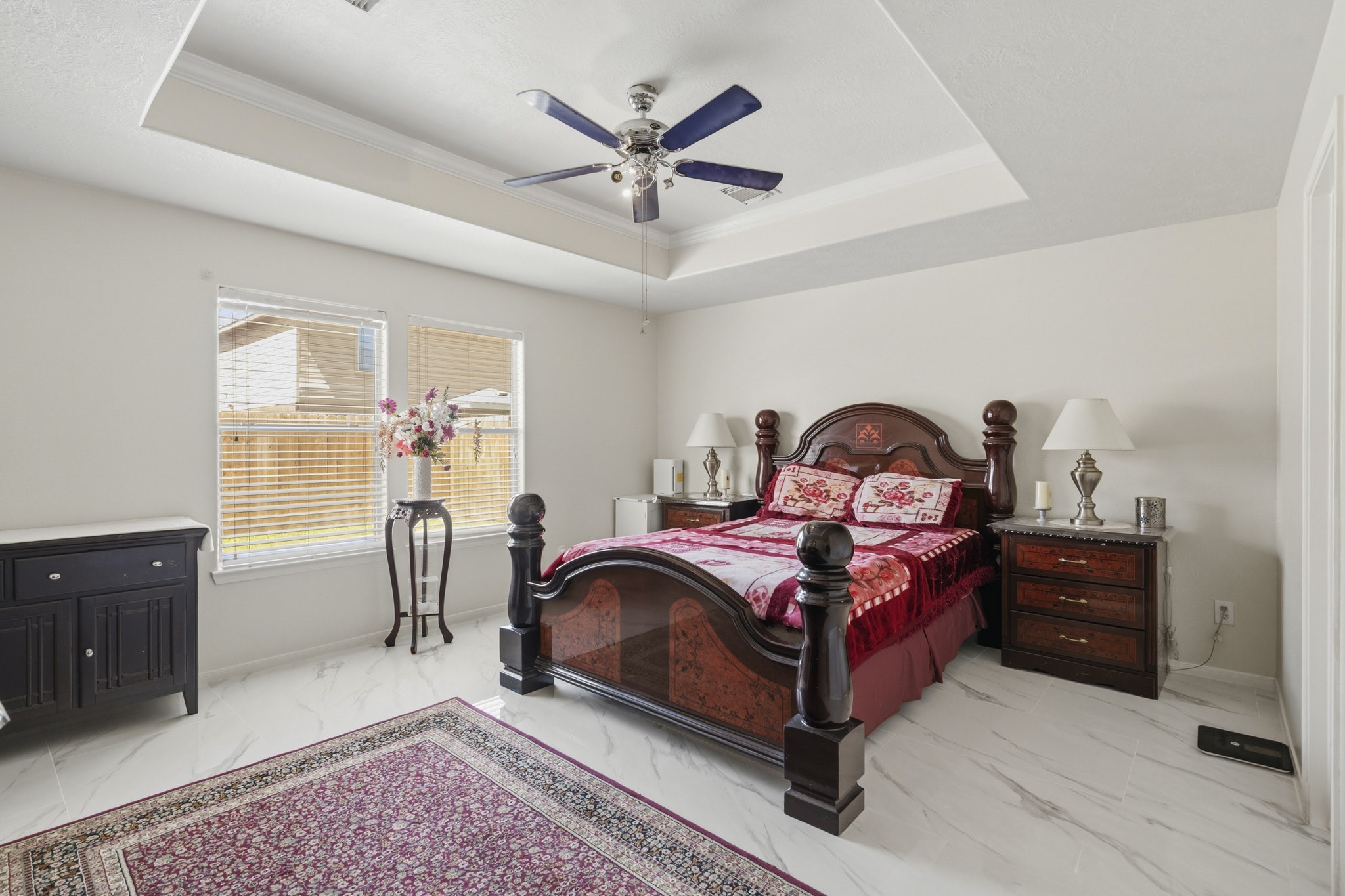 The spacious primary bedroom offers a recessed ceiling, ceiling fan and plenty of room to create a relaxing personal retreat.