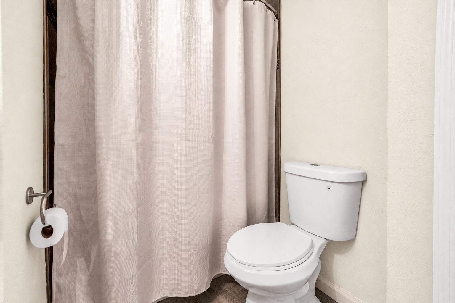 Cozy bathroom featuring a classic white toilet and a simple shower offering a clean and functional space.