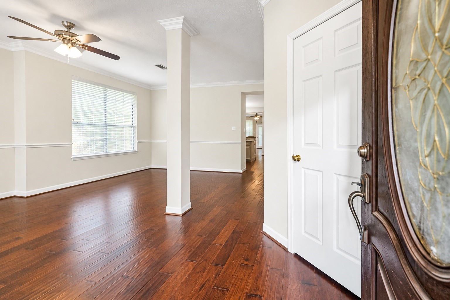 Inviting entryway with rich hardwood floors, elegant crown molding, and abundant natural light, leading to an open living space with a ceiling fan for comfort. Inviting entryway with rich hardwood floors, elegant crown molding, and abundant natural light, leading to an open living space with a ceiling fan for comfort.
