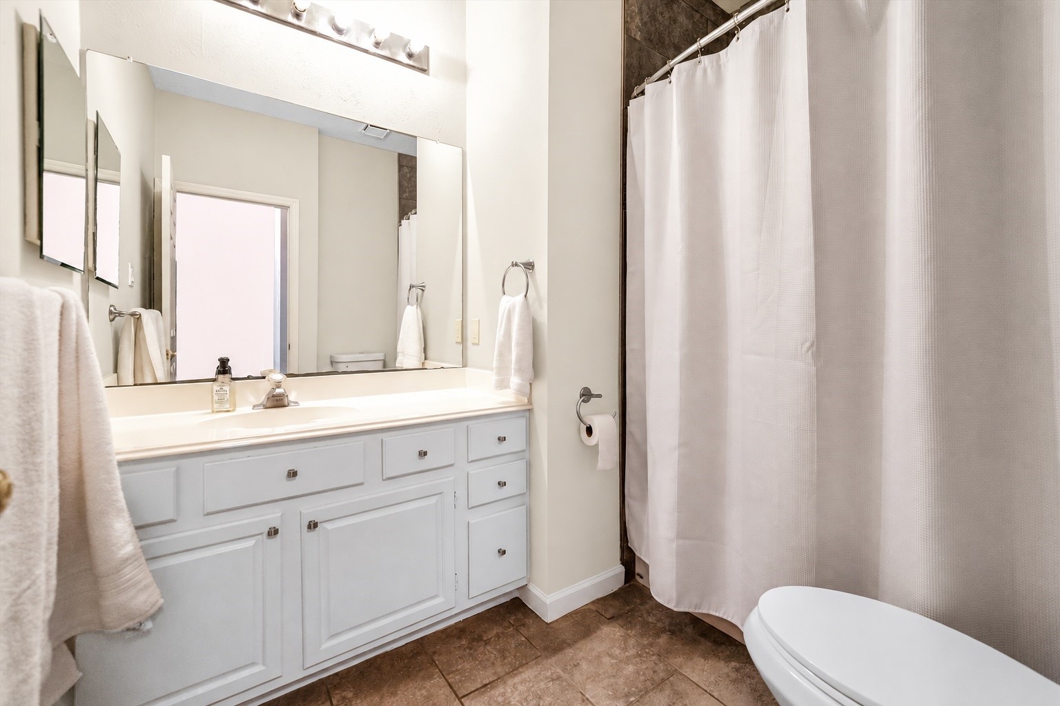 Bright and inviting bathroom with a large vanity, ample storage, and a clean shower area.