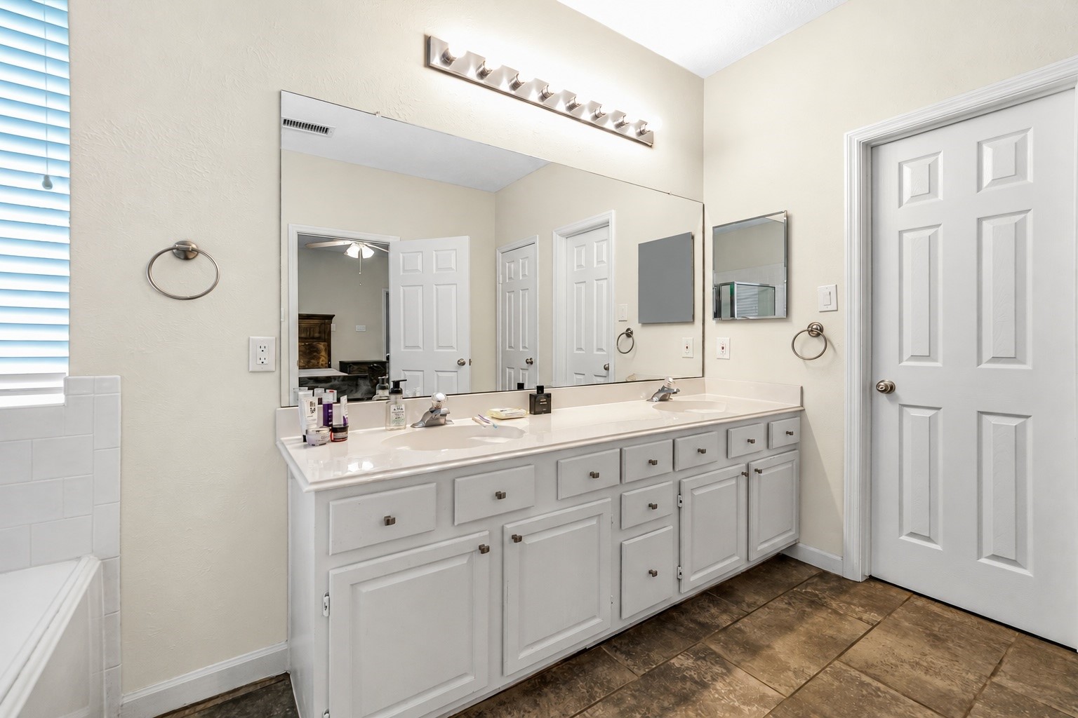 Spacious bathroom featuring dual sinks with ample counter space, plenty of storage in the white cabinetry, and a large mirror enhancing the room's brightness.