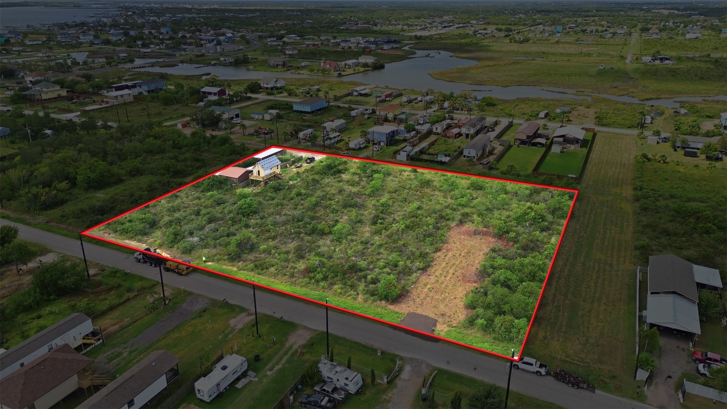 Angled aerial with the approximate boundary outlined in red. It shows the tract's size and shape relative to the street and surrounding properties.