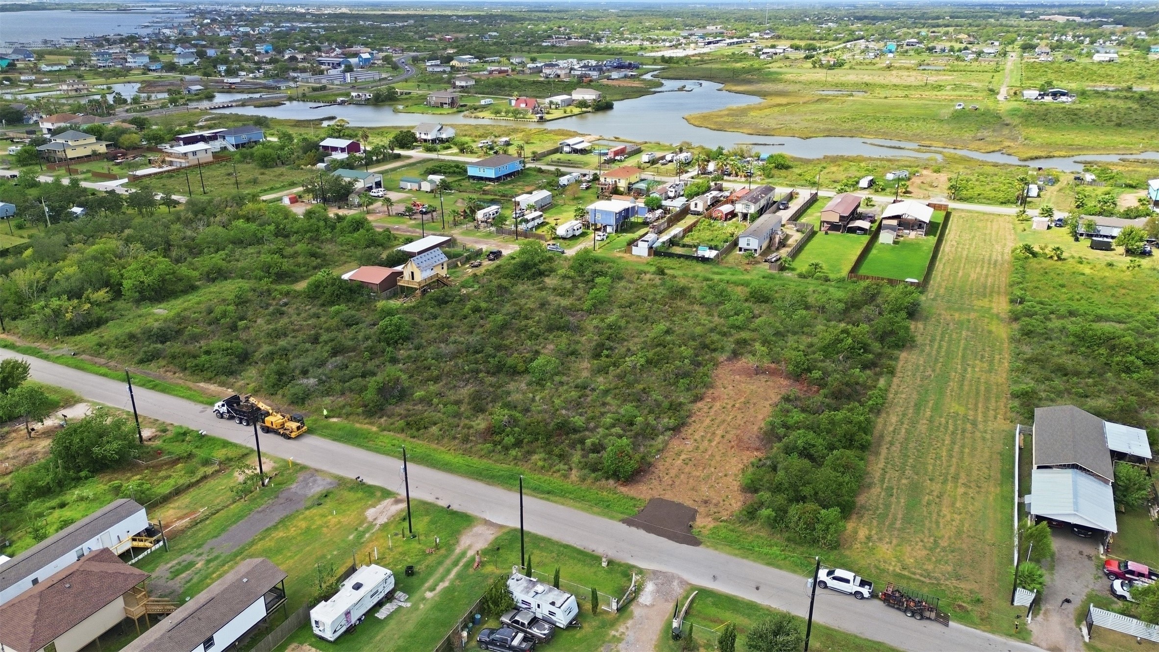 Wide aerial showing the property with the winding tidal waterway and marsh beyond. It highlights the coastal setting and open surroundings.