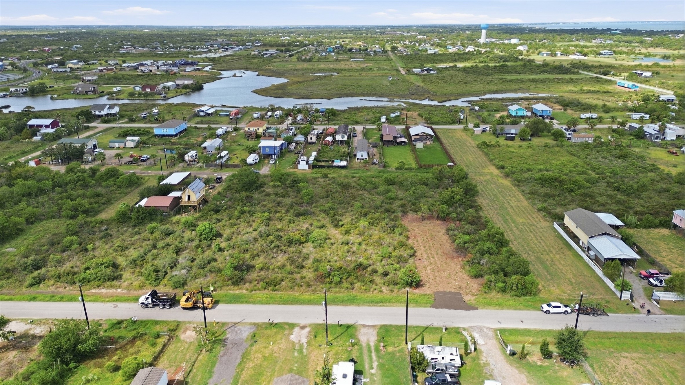 Low-angle aerial from the road. A water tower and the broader community are visible in the distance, which shows how established the area is.