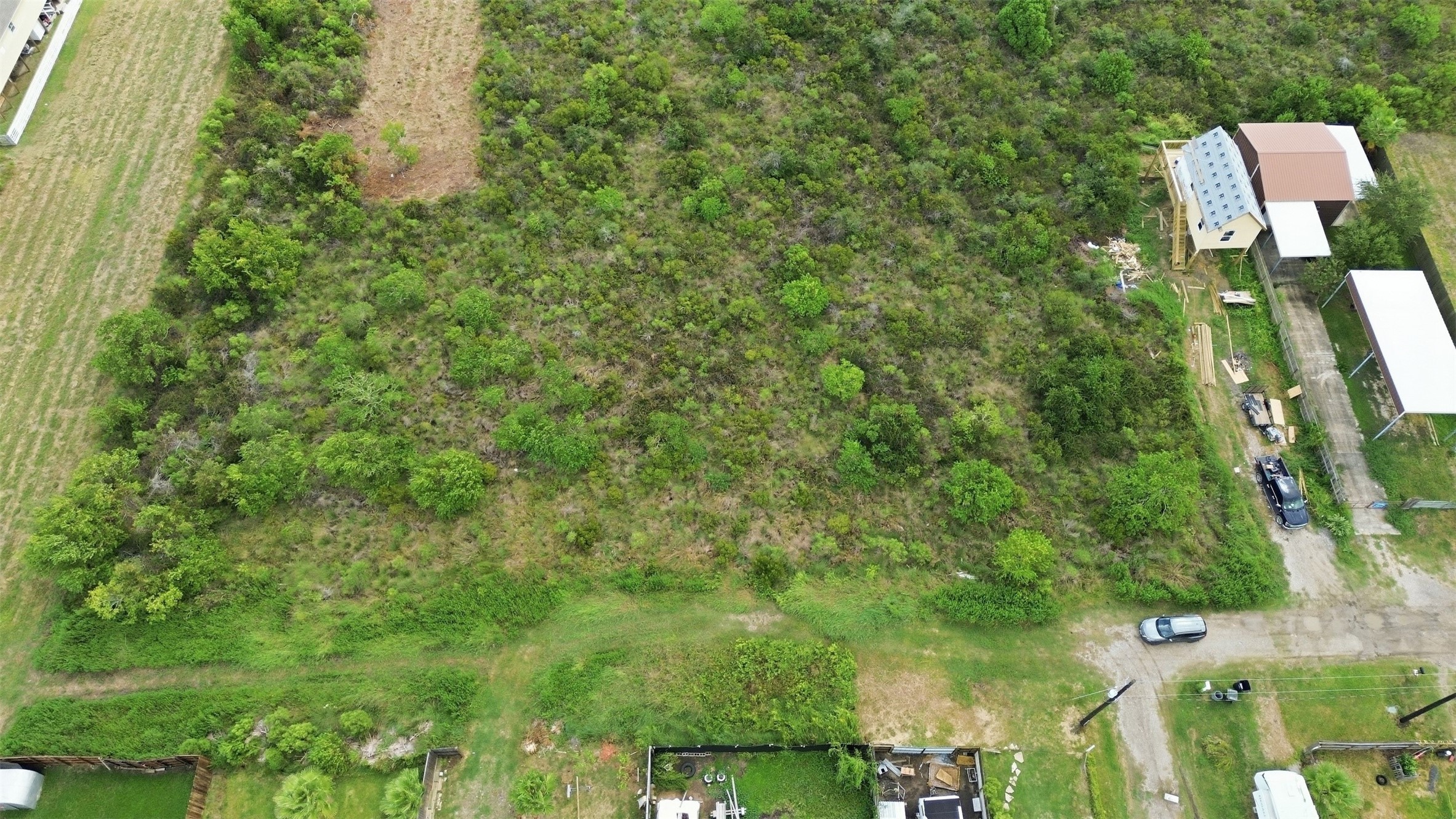 Overhead view of the lot covered in native coastal brush and scattered trees. A cleared section is visible along the front.