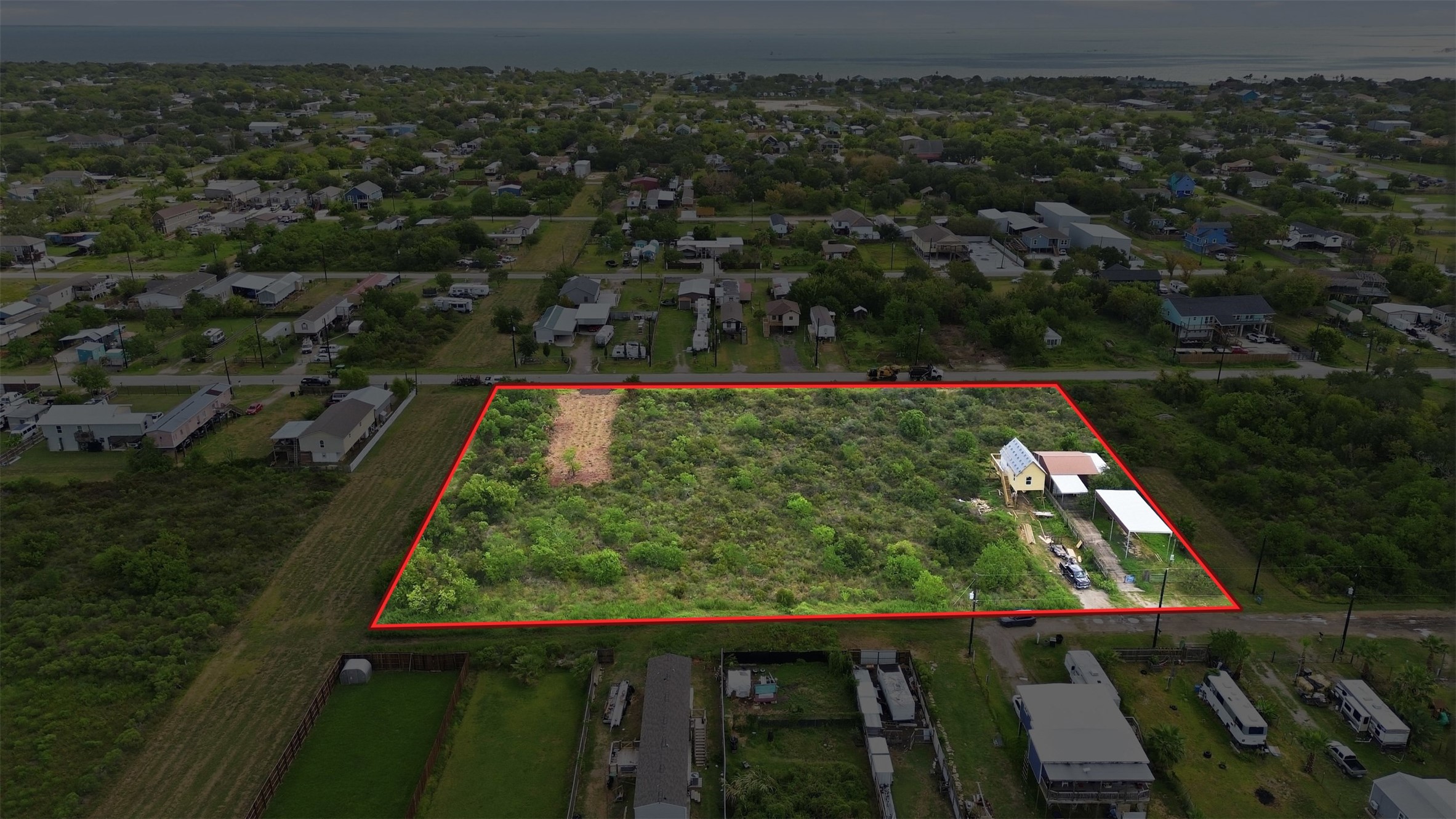 Open San Leon tract with paved street frontage, gravel road access on the side, and neighboring homes close by. Cleared pad and driveway apron already in place, minutes from Galveston Bay and ready for a coastal home or investment.