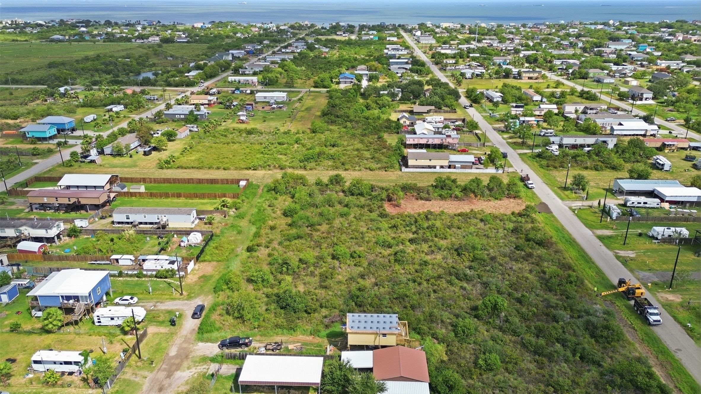 View from the back of the tract toward the road. It shows the lot's depth, the neighboring homes, and the bay in the distance.