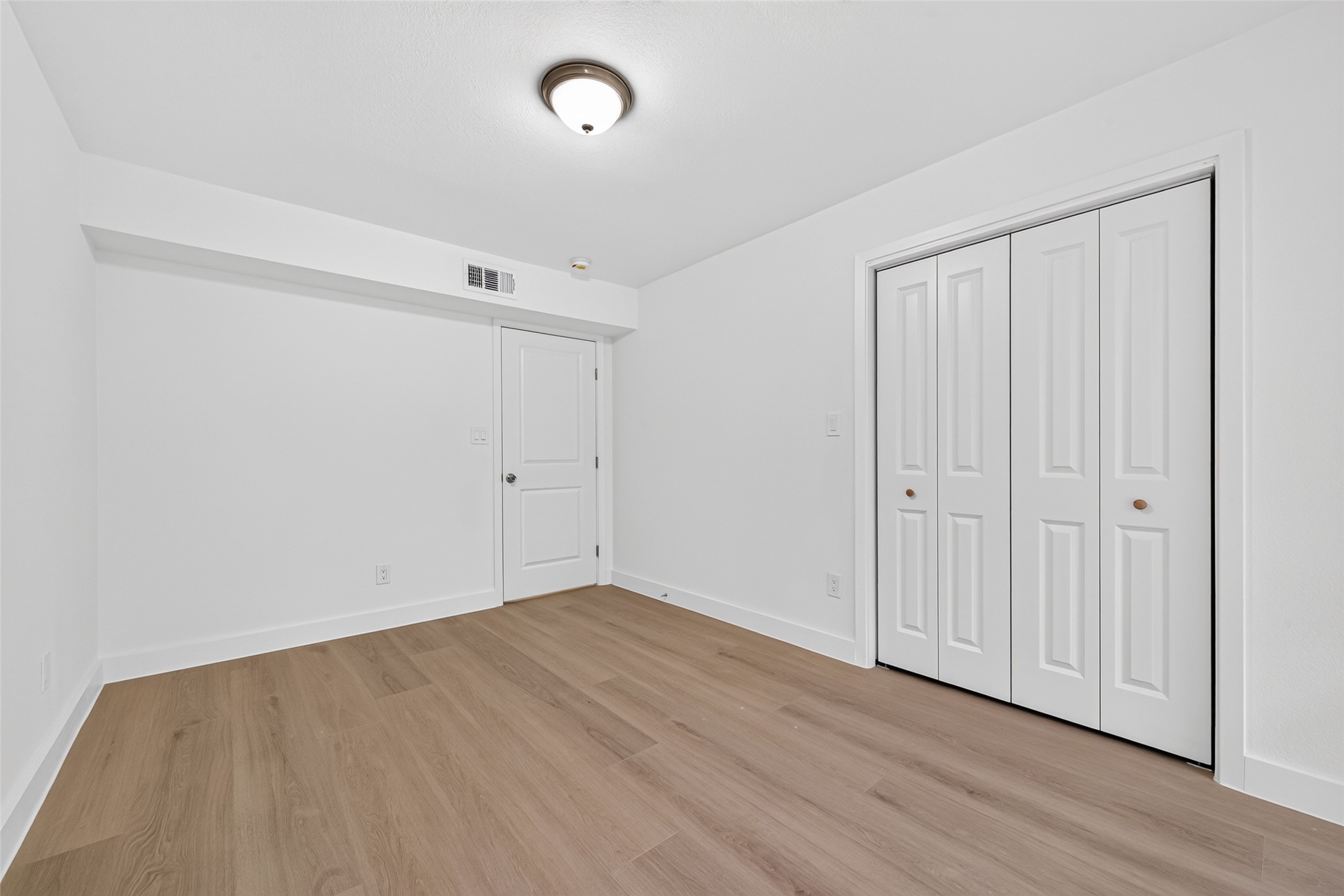 Versatile second bedroom featuring new laminate flooring, neutral finishes, and a welcoming atmosphere with no carpet.
