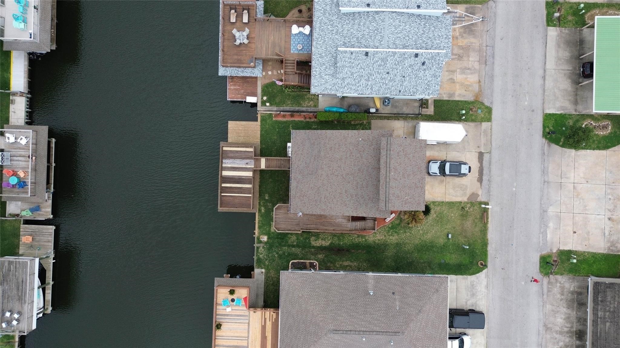 This aerial photo showcases a waterfront property with a private dock, situated along a canal. The home features a spacious outdoor deck, and the surrounding neighborhood appears well-maintained, with nearby homes also having access to the water.