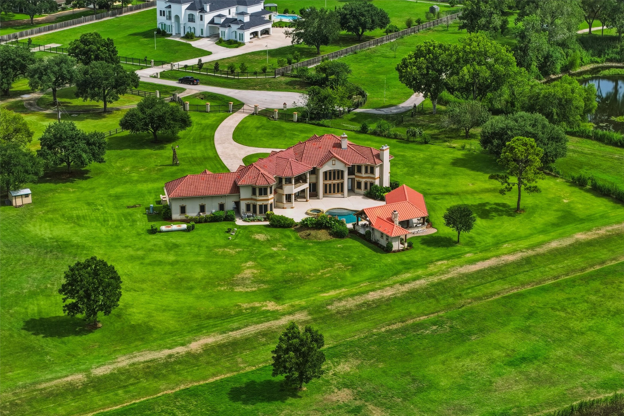 This breathtaking aerial perspective highlights the estate's generous acreage, sparkling pool, and covered outdoor living areas, all nestled within a serene and expansive natural landscape.