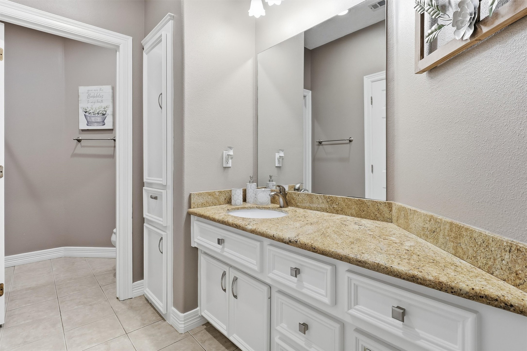 This well-appointed secondary bathroom includes a granite-topped vanity, a full entry linen closet, and easy access to the adjoining bedroom, offering both comfort and convenience.
