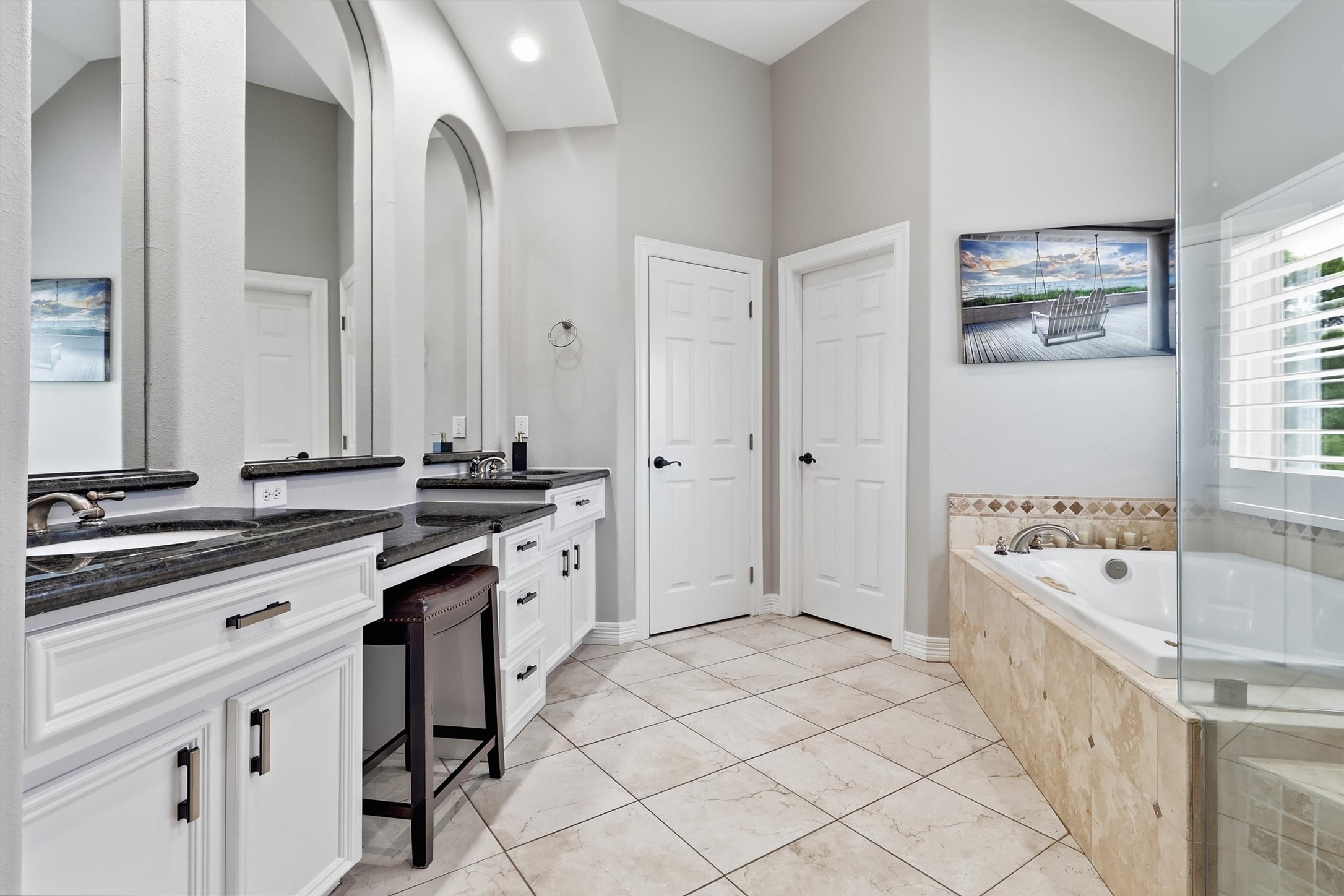 This spa-like primary bathroom offers dual vanities with granite countertops, an elevated jetted tub, and a private water closet. A full entry closet just off the space provides ample storage.