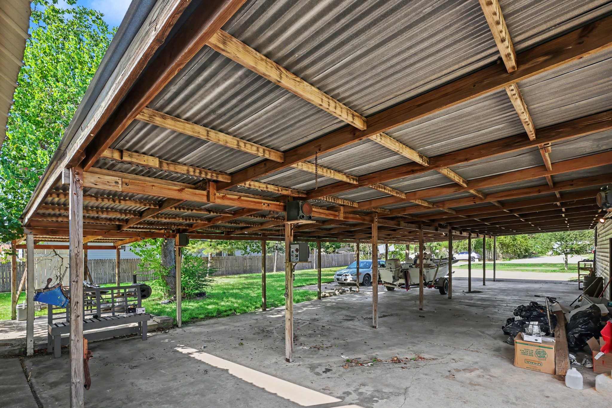 Expansive covered patio and carport with a concrete surface and ample space for parking
