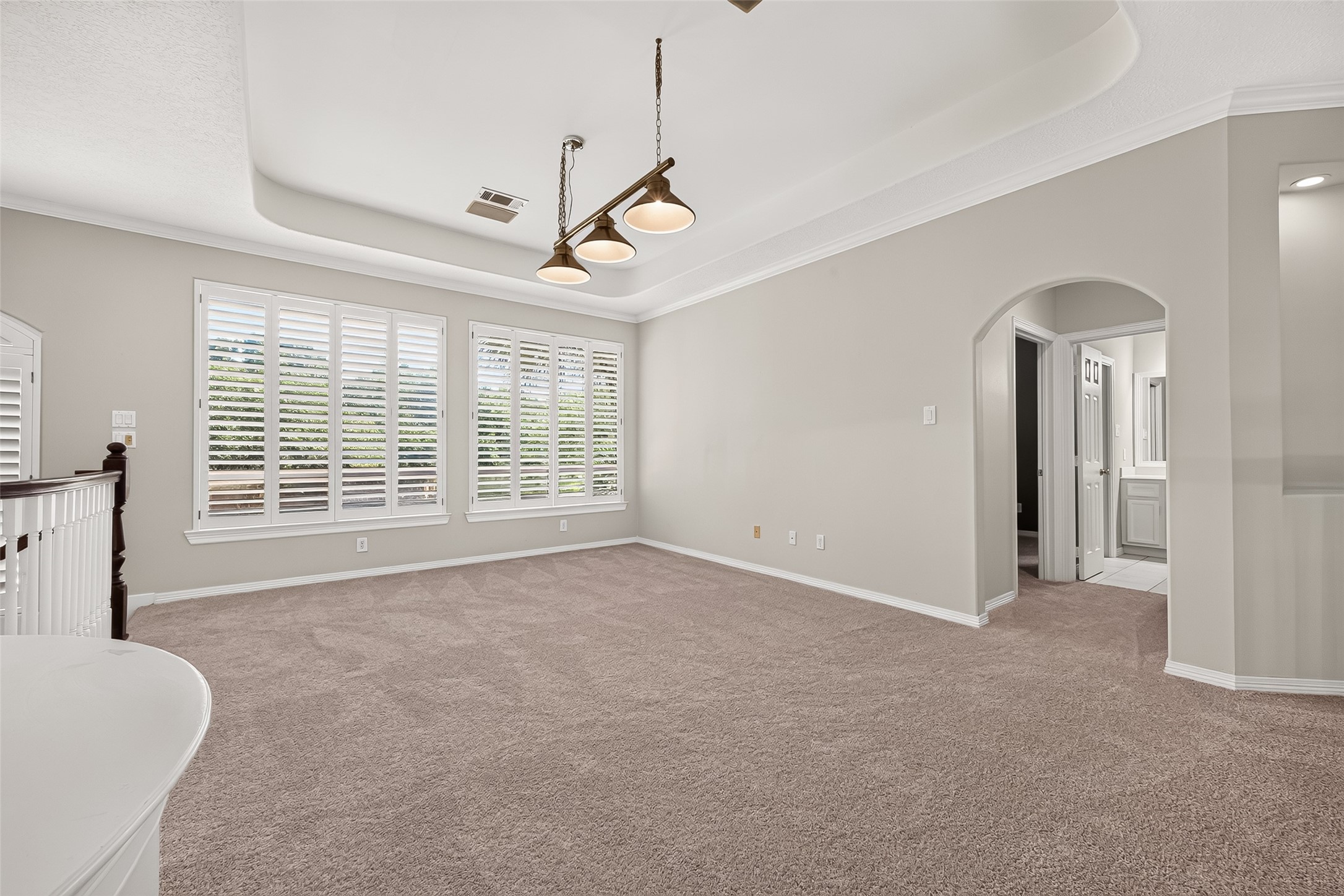 Spacious and bright game room area off the stairs landing. Notice the large windows with beautiful plantation shutters, elegant tray ceiling, and plush carpeting.