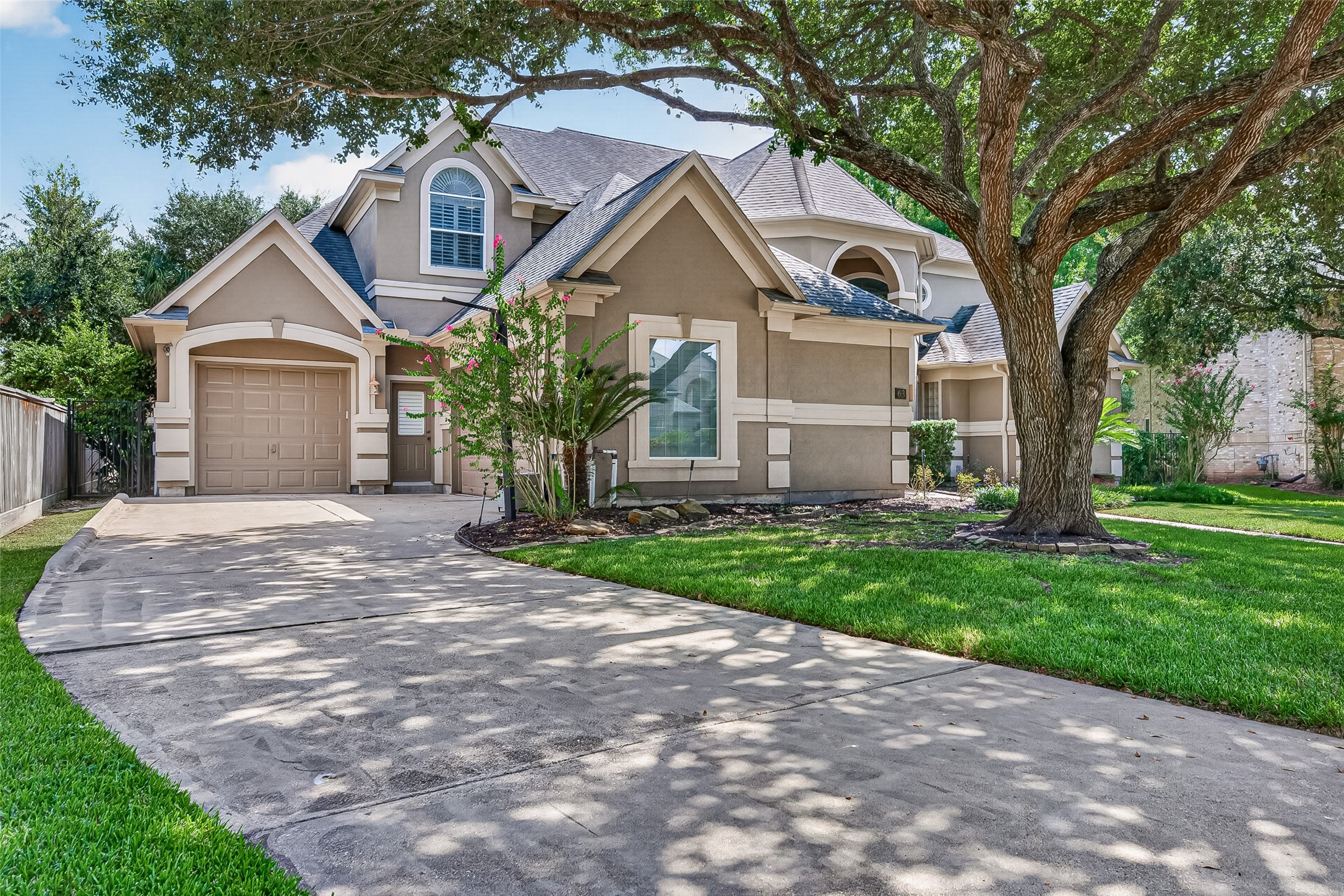 Charming two-story home with a manicured front lawn and mature tree providing shade. 3-car garage with an extended driveway for ample parking.