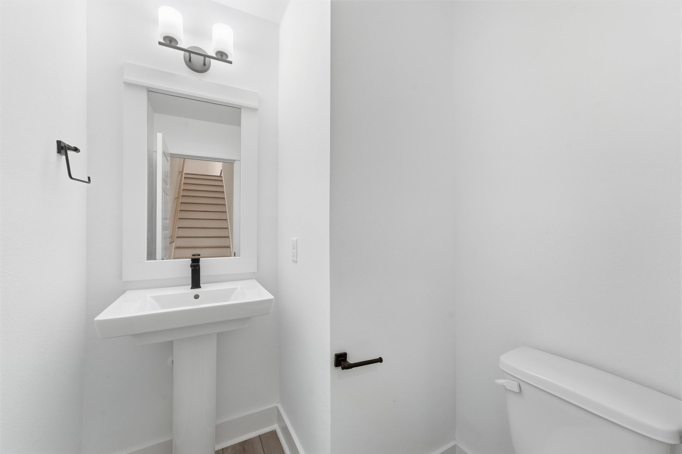 Half bath with a pedestal sink and modern matte black fixtures.