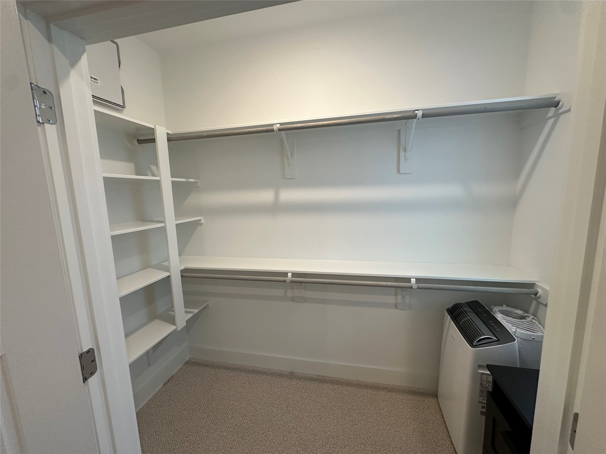 Spacious primary walk-in closet with double hanging rods and built-in shelving.