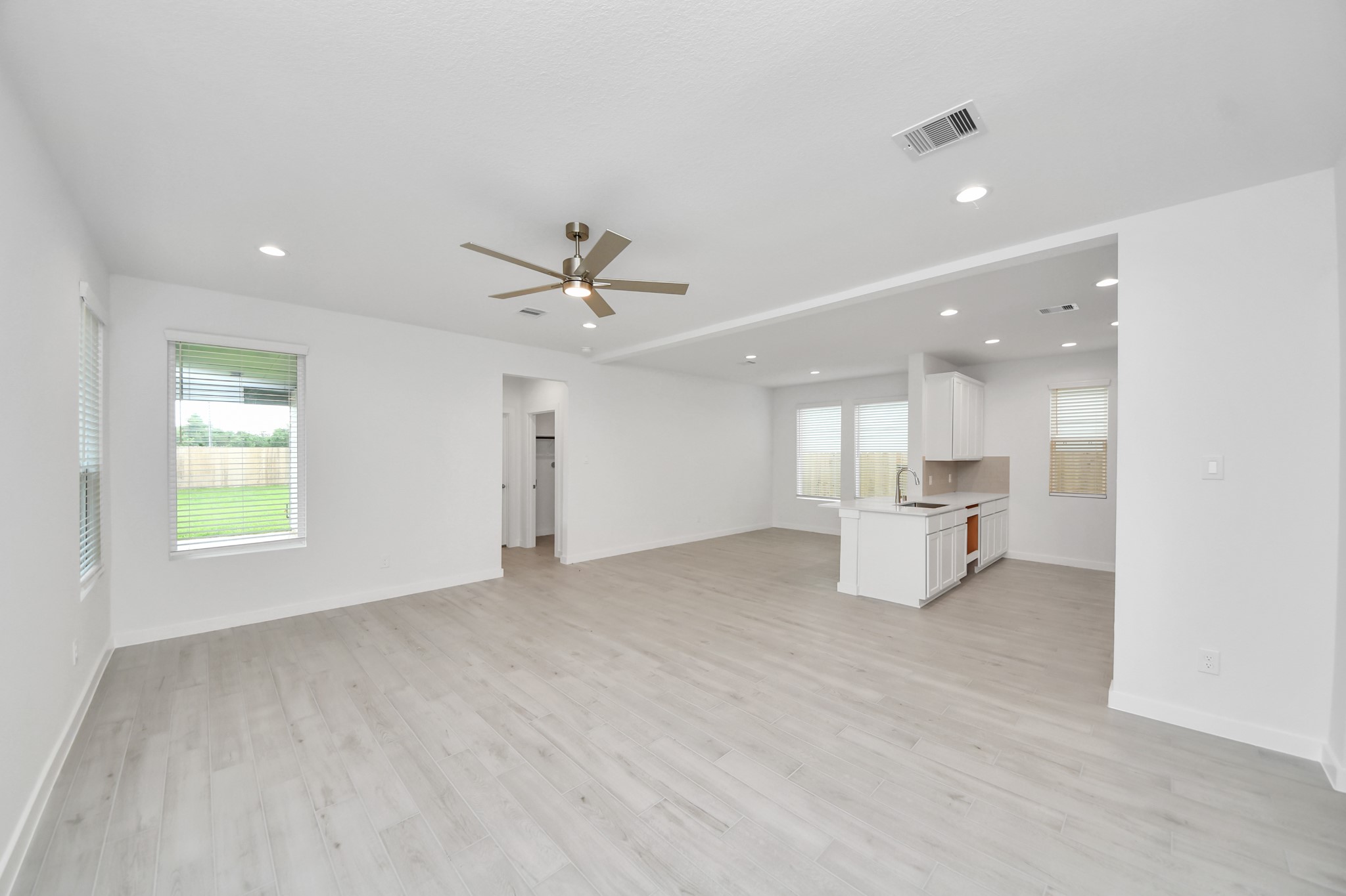 Welcome family and guests to your charming living room! With its high ceilings, recessed lighting, ceiling fan, custom paint, beautiful flooring, and large windows that let in abundant natural light, this room is perfect for gatherings. Sample photo of completed home with similar floor plan. Actual colors and selections may vary.
