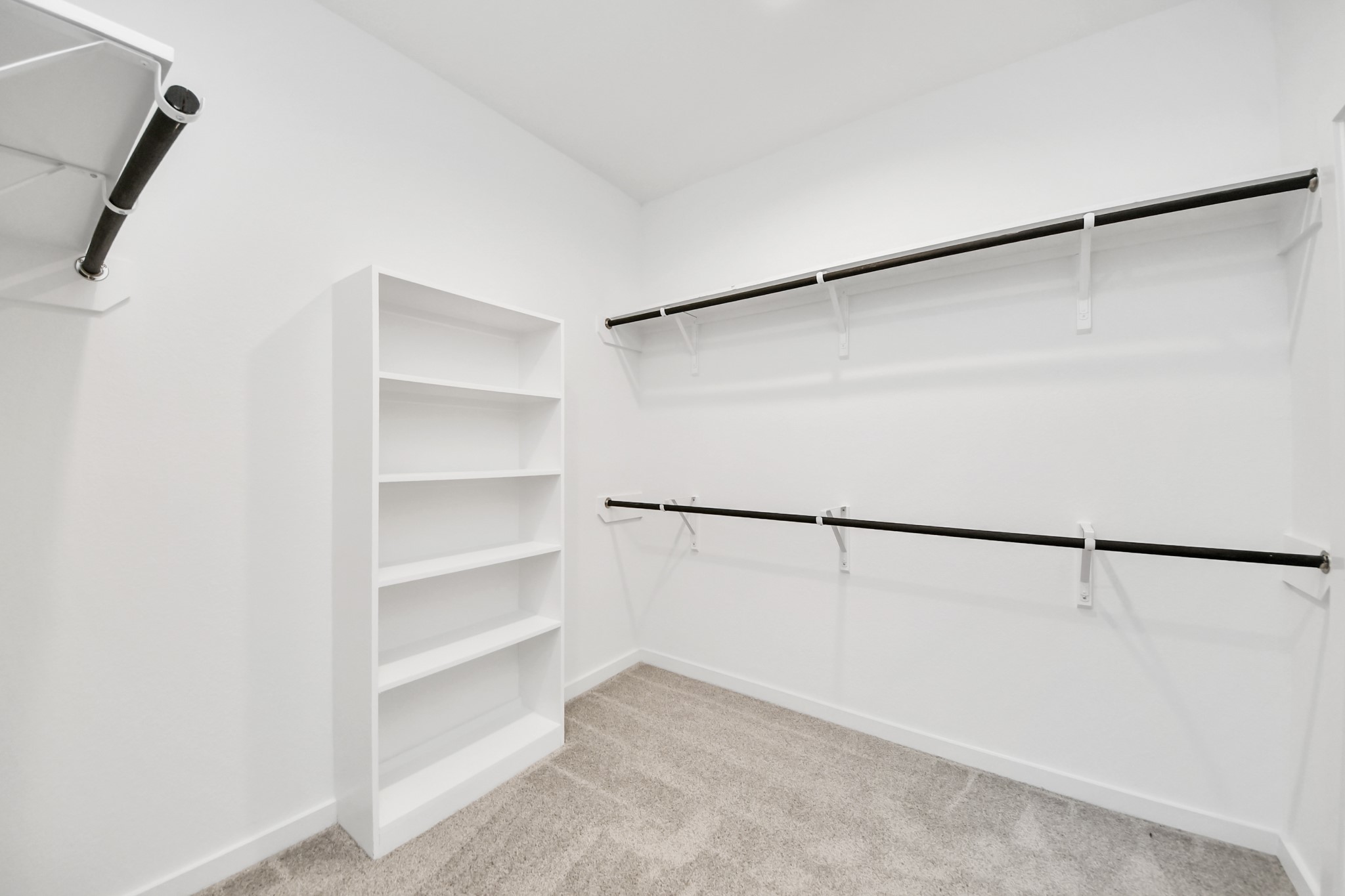 Walk-in closet that epitomizes luxury and practicality. This generously sized space features built-in shelving, offering abundant room for impeccable organization. High ceilings and recessed lighting create a bright and welcoming ambiance. Sample photo of completed home with similar floor plan. Actual colors and selections may vary.