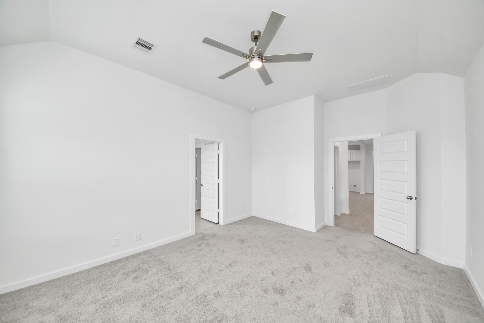 Escape and relax in the exquisite primary suite, a haven to unwind after a long day. The spacious room, located on first floor, boasts plush carpeting, soothing paint tones, high ceilings, and expansive windows adorned with privacy blinds. Sample photo of completed home with similar floor plan. Actual colors and selections may vary.
