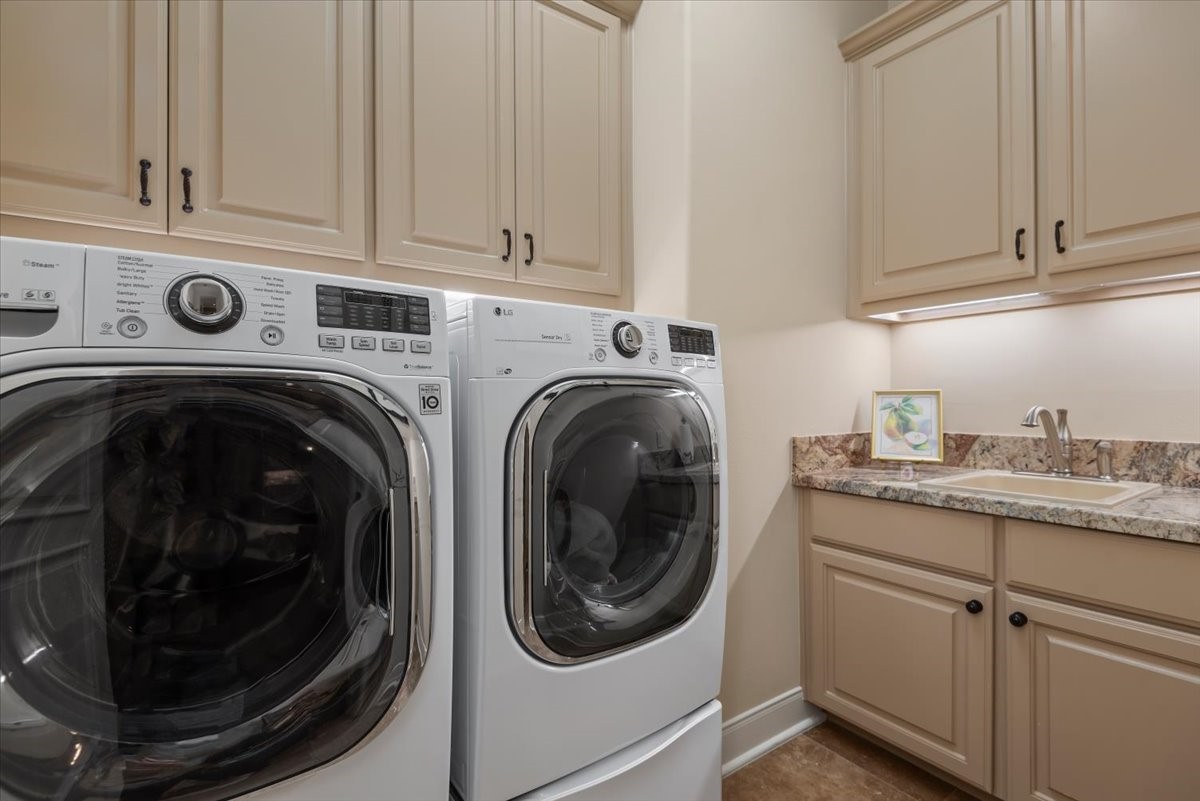 The utility room features tons of cabinets and a handy sink!