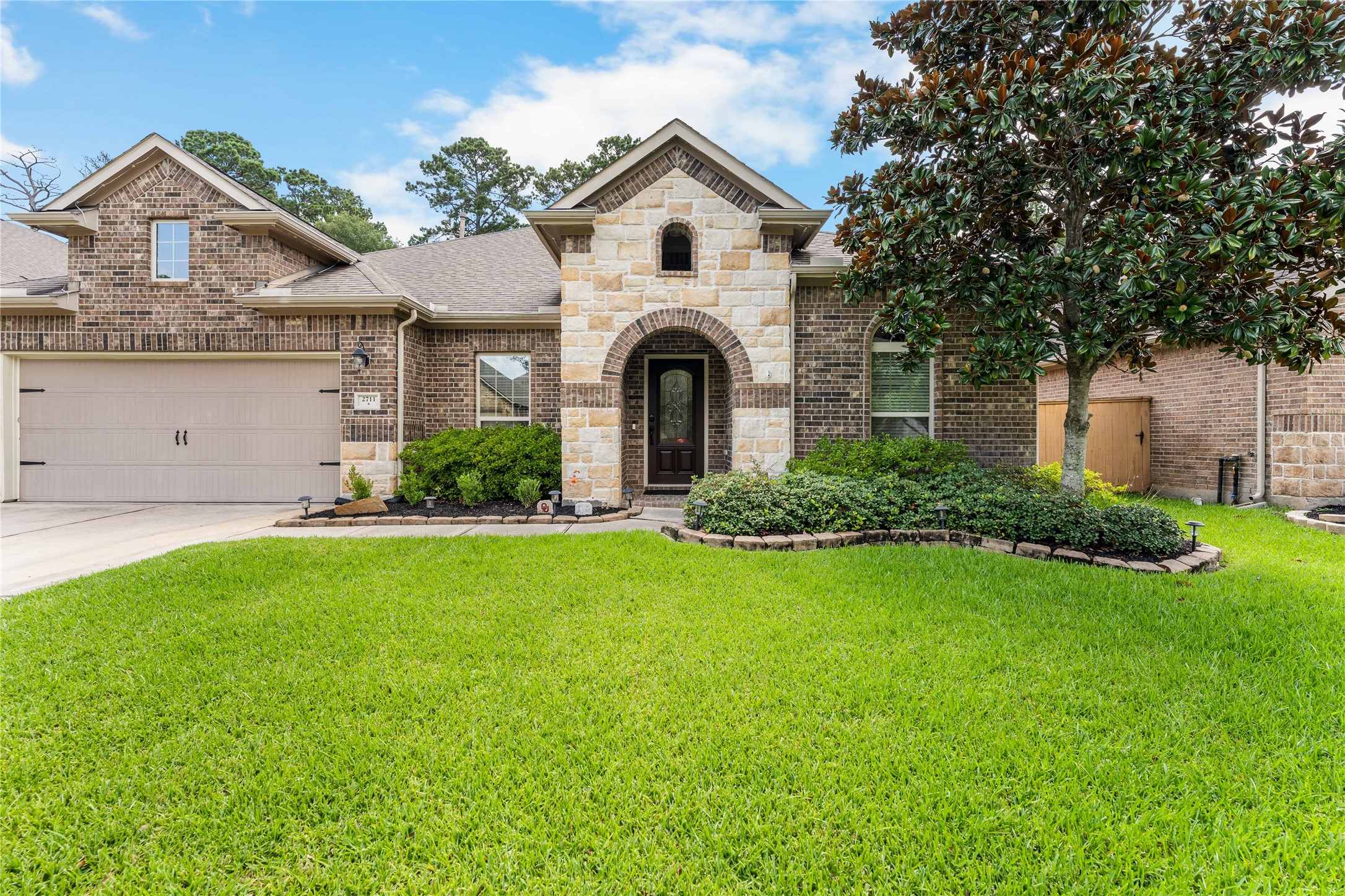 Front elevation showcasing timeless brick and stone architecture with manicured landscaping in Graystone Hills. Front elevation showcasing timeless brick and stone architecture with manicured landscaping in Graystone Hills.