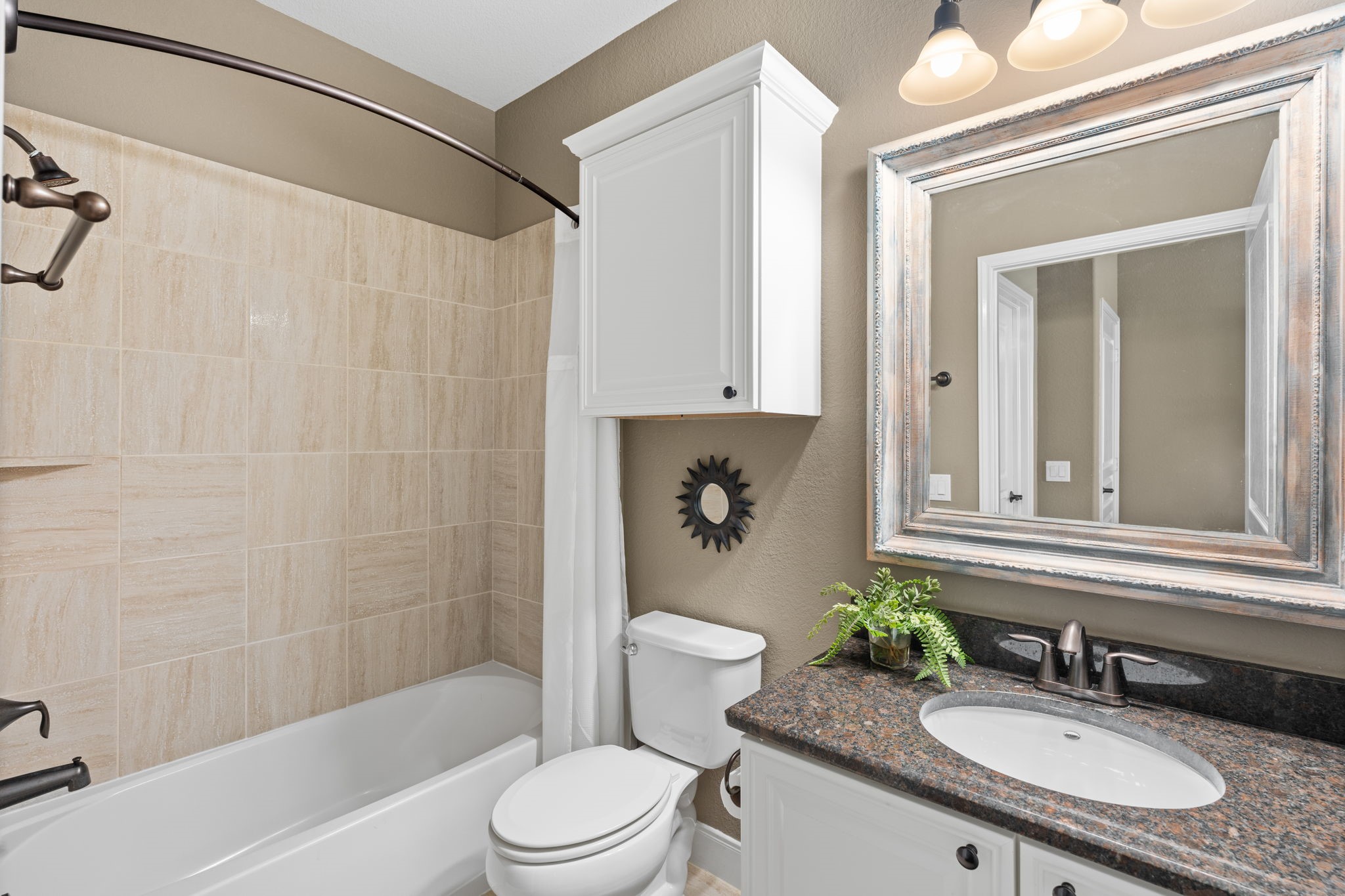Guest bath - discover a space that exudes charm and character. Framed mirror adds a touch of artistic flair that instantly captures your attention. The tile with brushed bronze hardware makes the bathroom feel fresh and inviting.