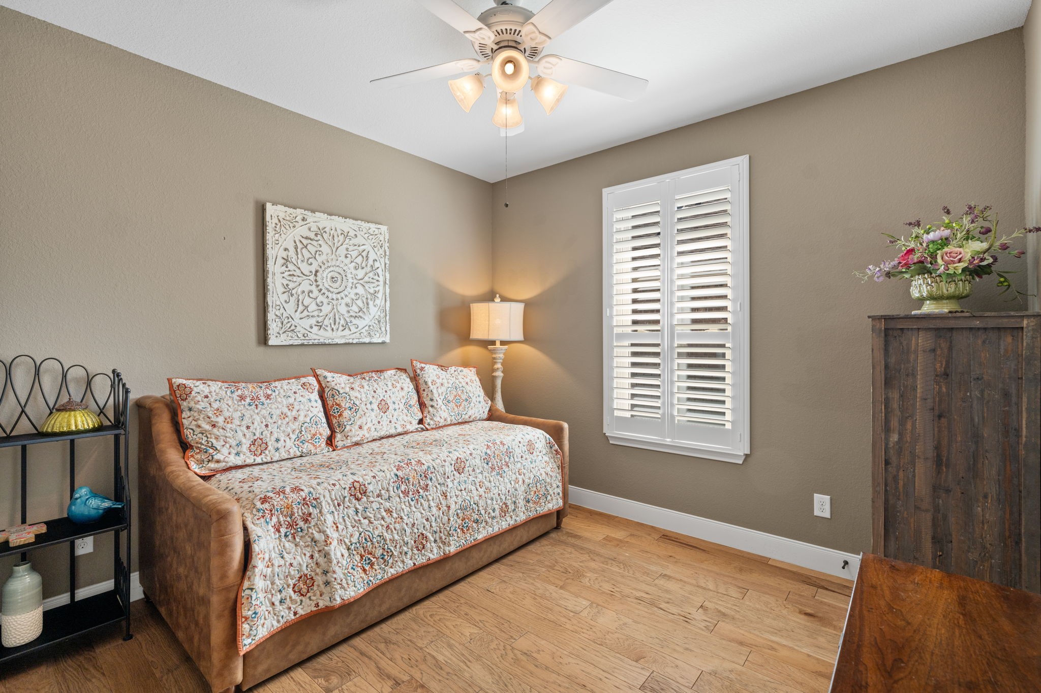 3rd bedroom with planation shutters and a fan.