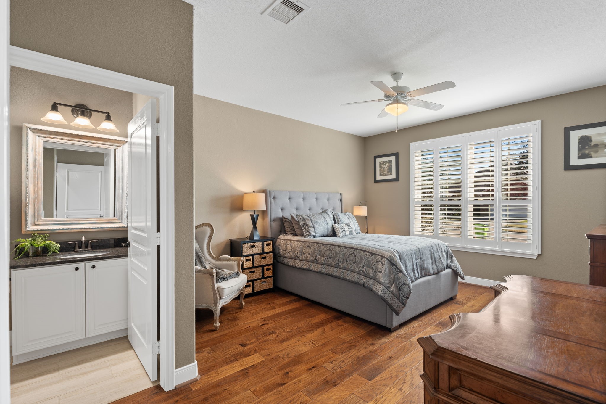 Welcome to the guest suite, a genuine sanctuary for visitors. Large windows, adorned w/plantation shutters, and the ensuite bathroom make it a welcoming space for visitors.
