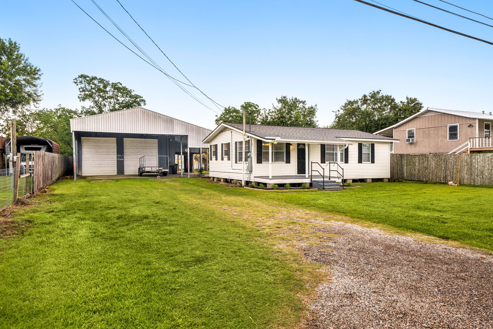 Charming single-story home with a welcoming front porch and spacious lawn. Features a large carport and a well-maintained fenced yard, perfect for family living. The house is set against a serene backdrop with mature trees, offering a peaceful neighborhood ambiance.