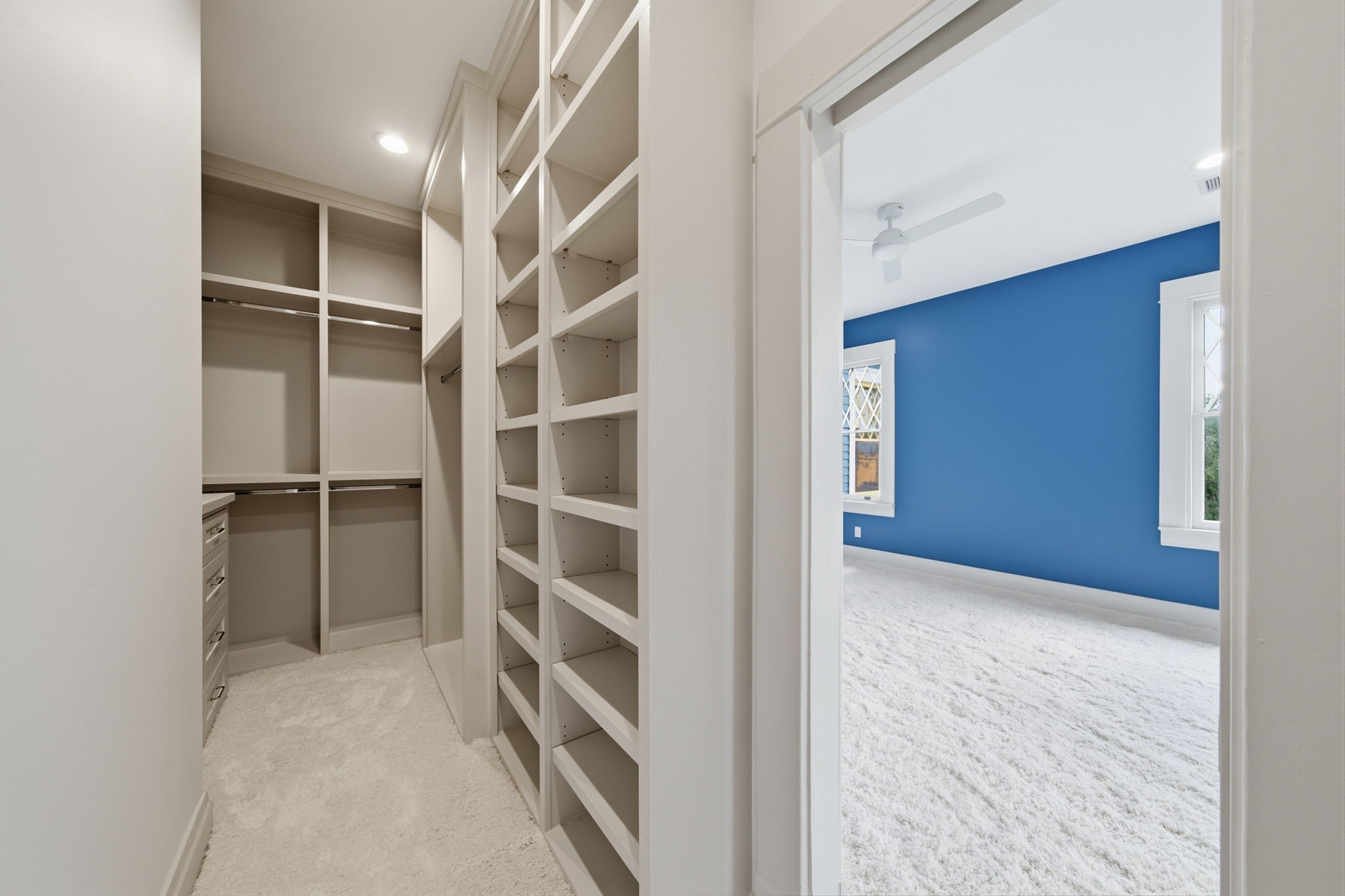 Large walk-in closet with ample shelving and dual closed cabinetry for storage.
